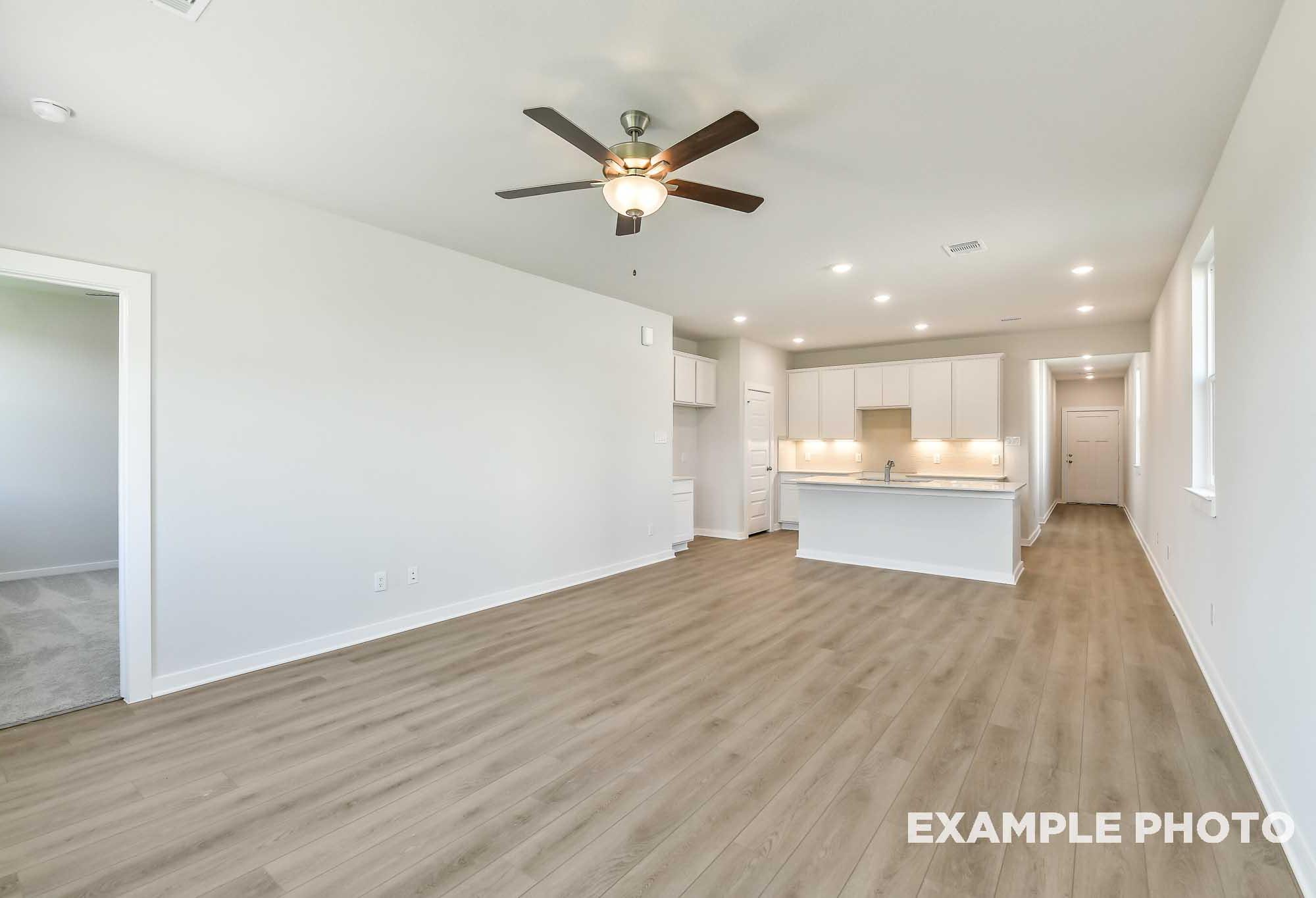 Open-concept living area and kitchen with island in The Colorado, a Davidson Homes single-family design in Beasley, Texas