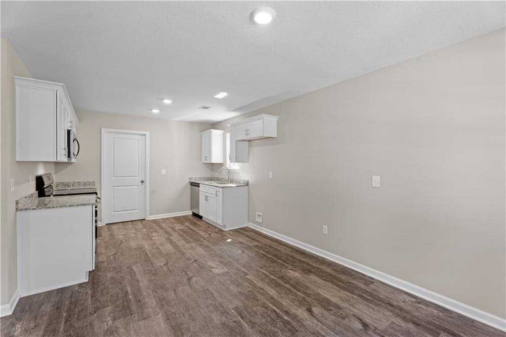 Modern white kitchen with cabinets, stainless sink, dishwasher, and hardwood floors in Davidson Homes The Washington, Phenix City, AL