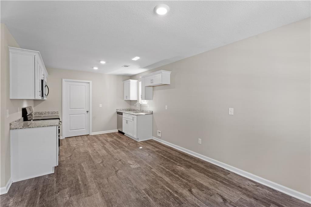 Modern white kitchen with cabinets, stainless sink, dishwasher, and hardwood floors in Davidson Homes The Washington, Phenix City, AL