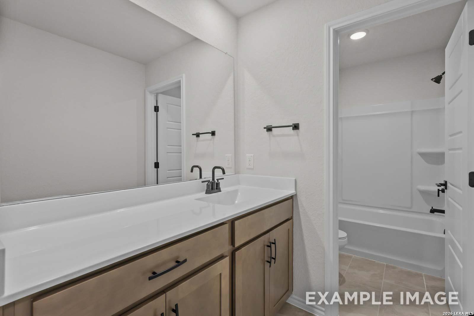 Modern bathroom with vanity, large mirror, and tub-shower combo in The Florence D floor plan by Davidson Homes.