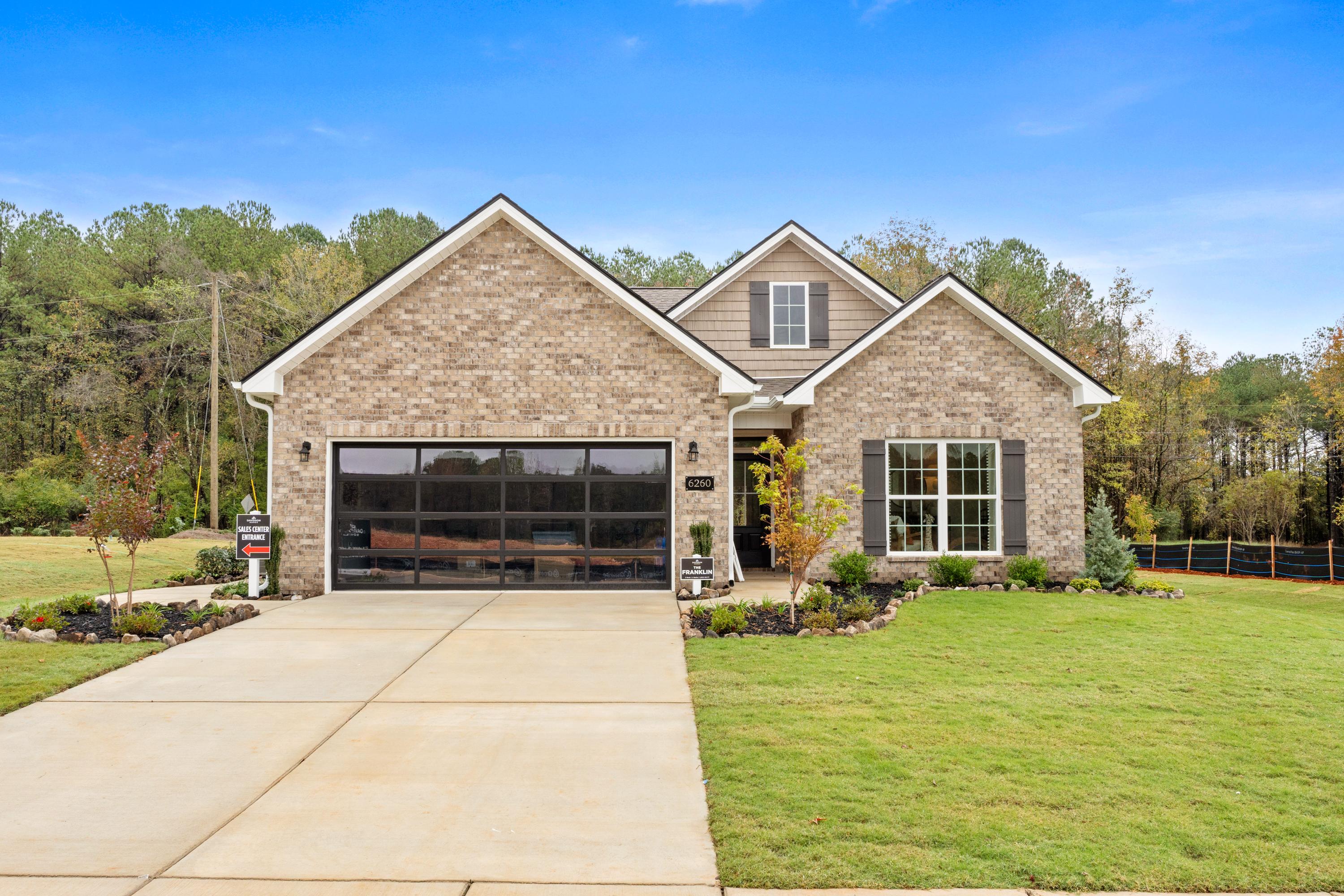 Brick Craftsman home exterior at Spragins Cove in Huntsville Alabama with attached garage, driveway and landscaped yard