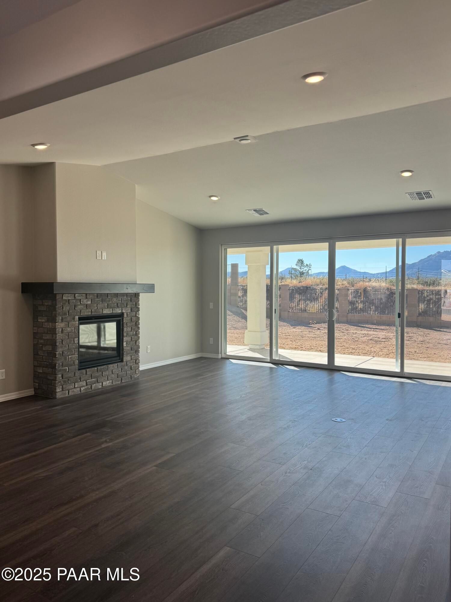 Modern great room featuring stone gas fireplace and sliding doors to desert mountain views in Davidson Homes The Monarch E, Prescott AZ