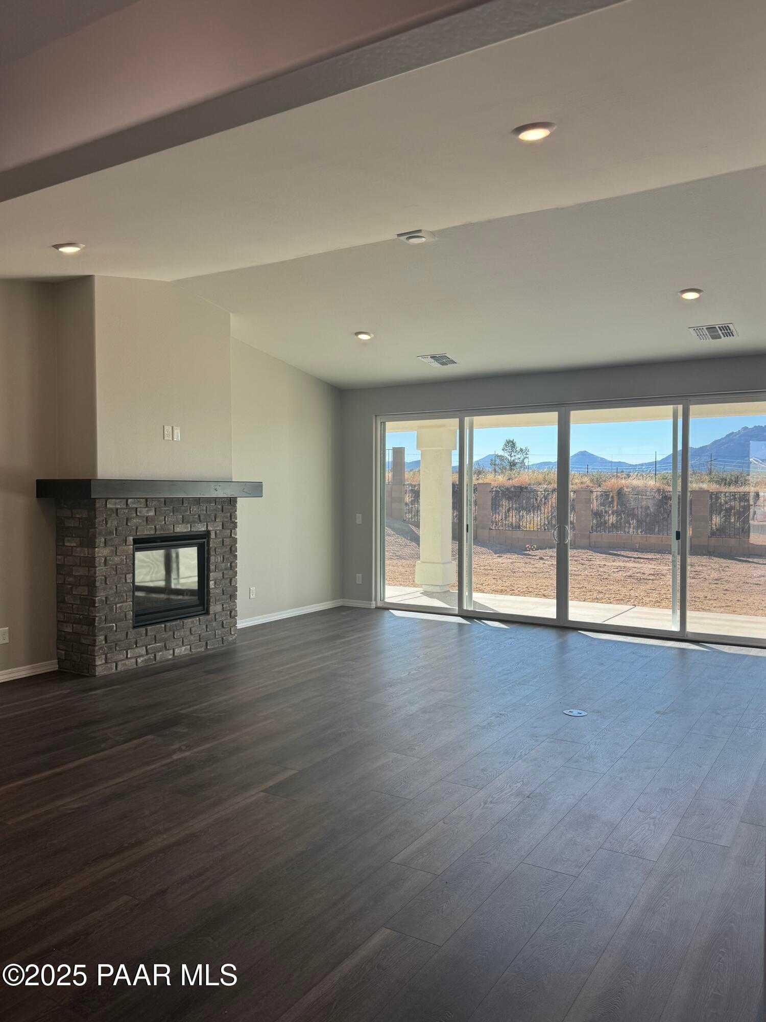 Modern great room featuring stone gas fireplace and sliding doors to desert mountain views in Davidson Homes The Monarch E, Prescott AZ