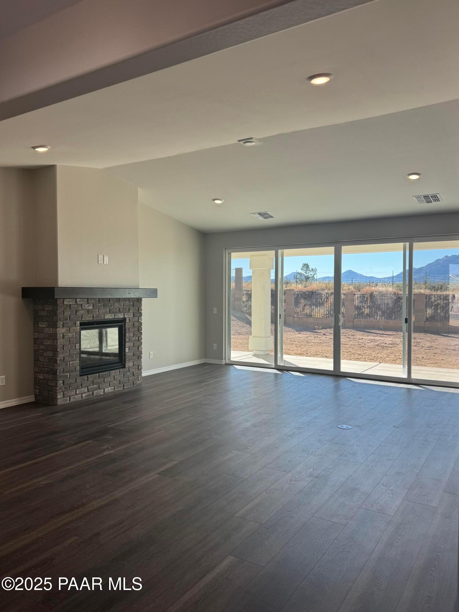Modern great room featuring stone gas fireplace and sliding doors to desert mountain views in Davidson Homes The Monarch E, Prescott AZ