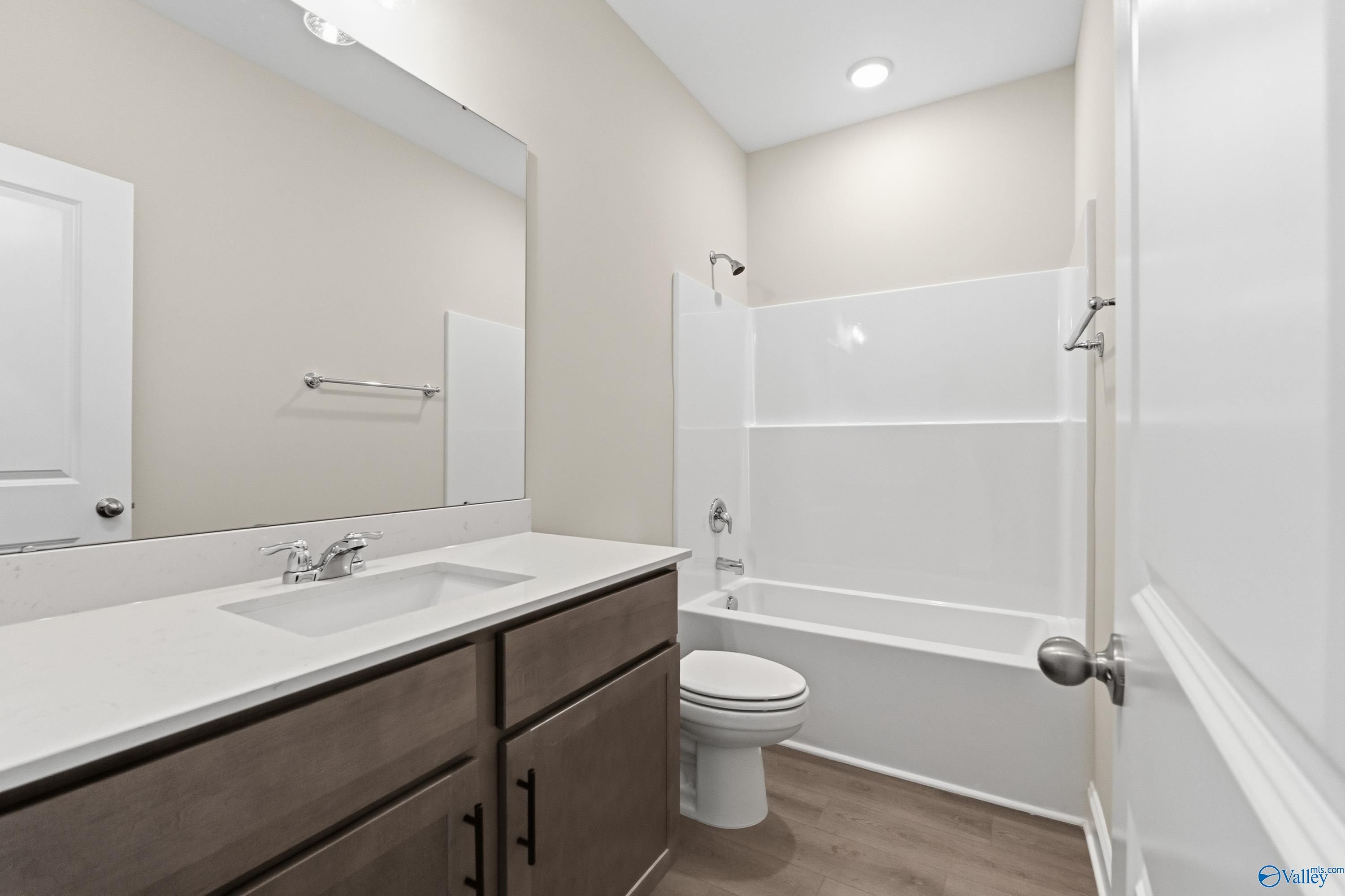 Modern bathroom with white tub-shower combo, single vanity, mirror, and neutral walls in Davidson Homes The Asheville C, Huntsville, AL