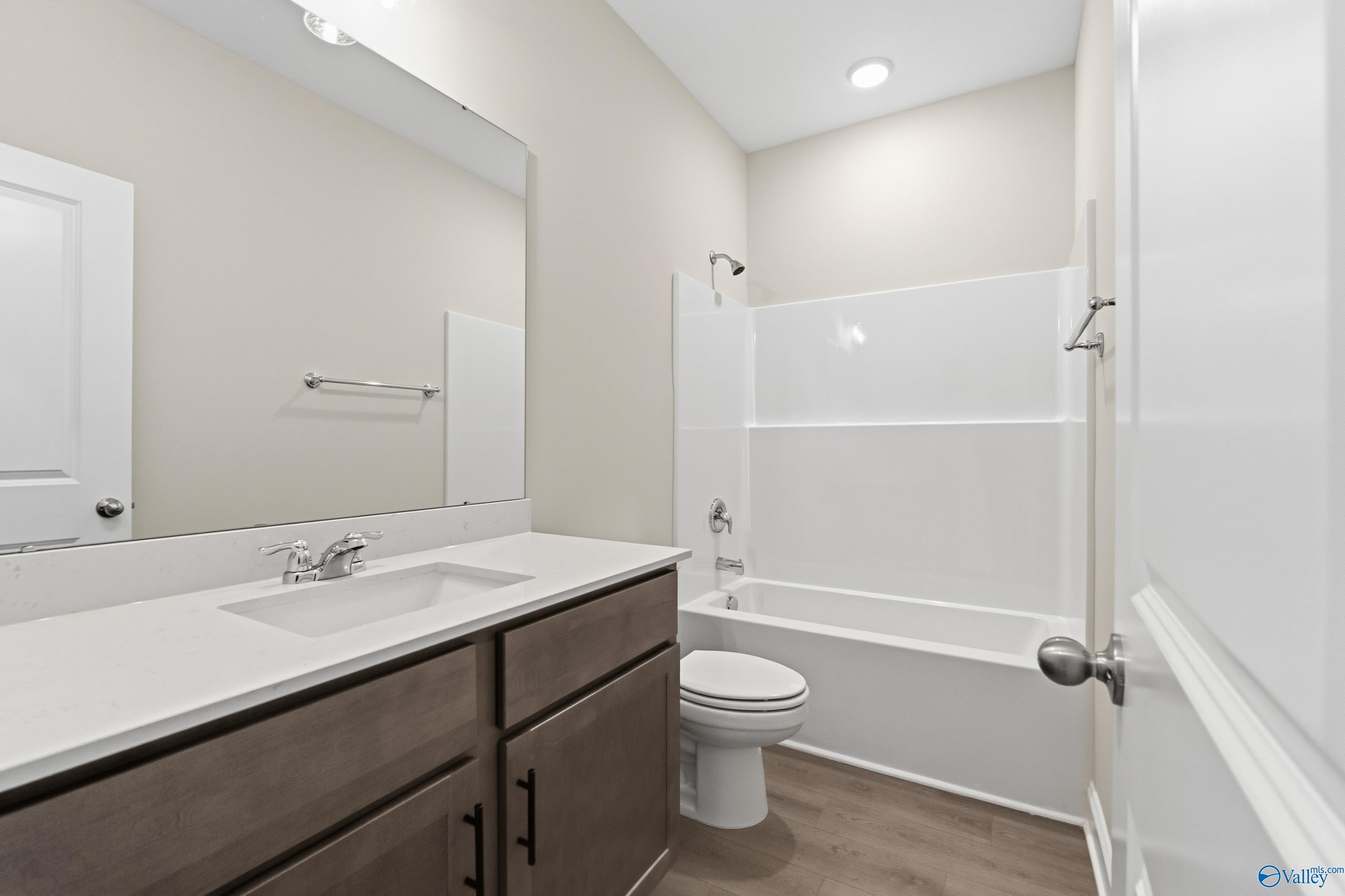 Modern bathroom with white tub-shower combo, single vanity, mirror, and neutral walls in Davidson Homes The Asheville C, Huntsville, AL