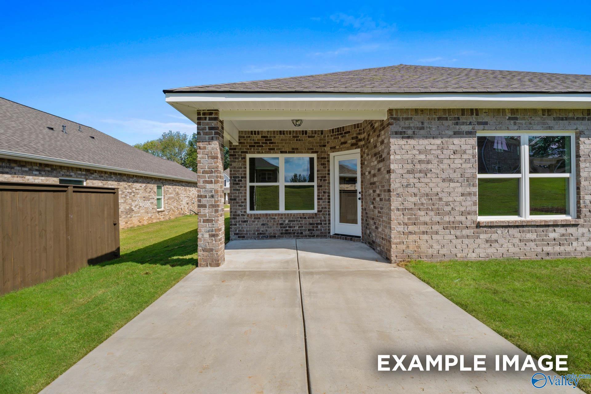 Brick 4-bedroom Daphne D home exterior with covered porch, driveway, and lush lawn in Walker's Hill, Meridianville, Alabama