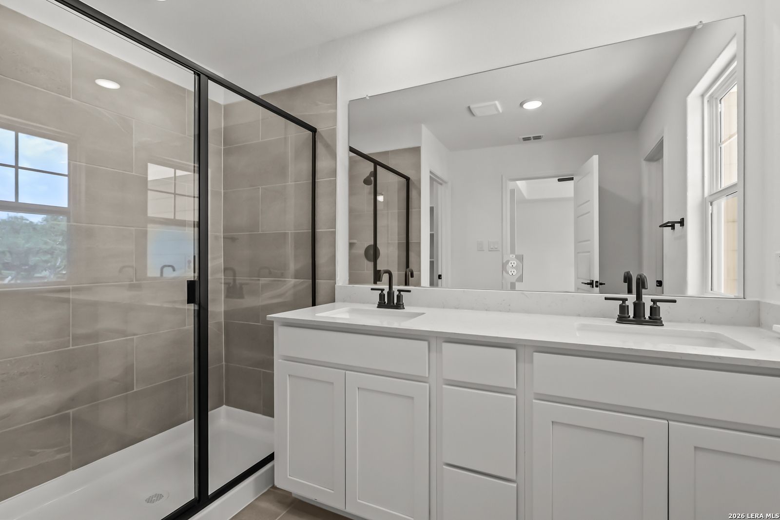 Modern bathroom with dual vanity and walk-in glass shower in The Florence B floor plan at Meadows at Oak Creek, San Antonio.