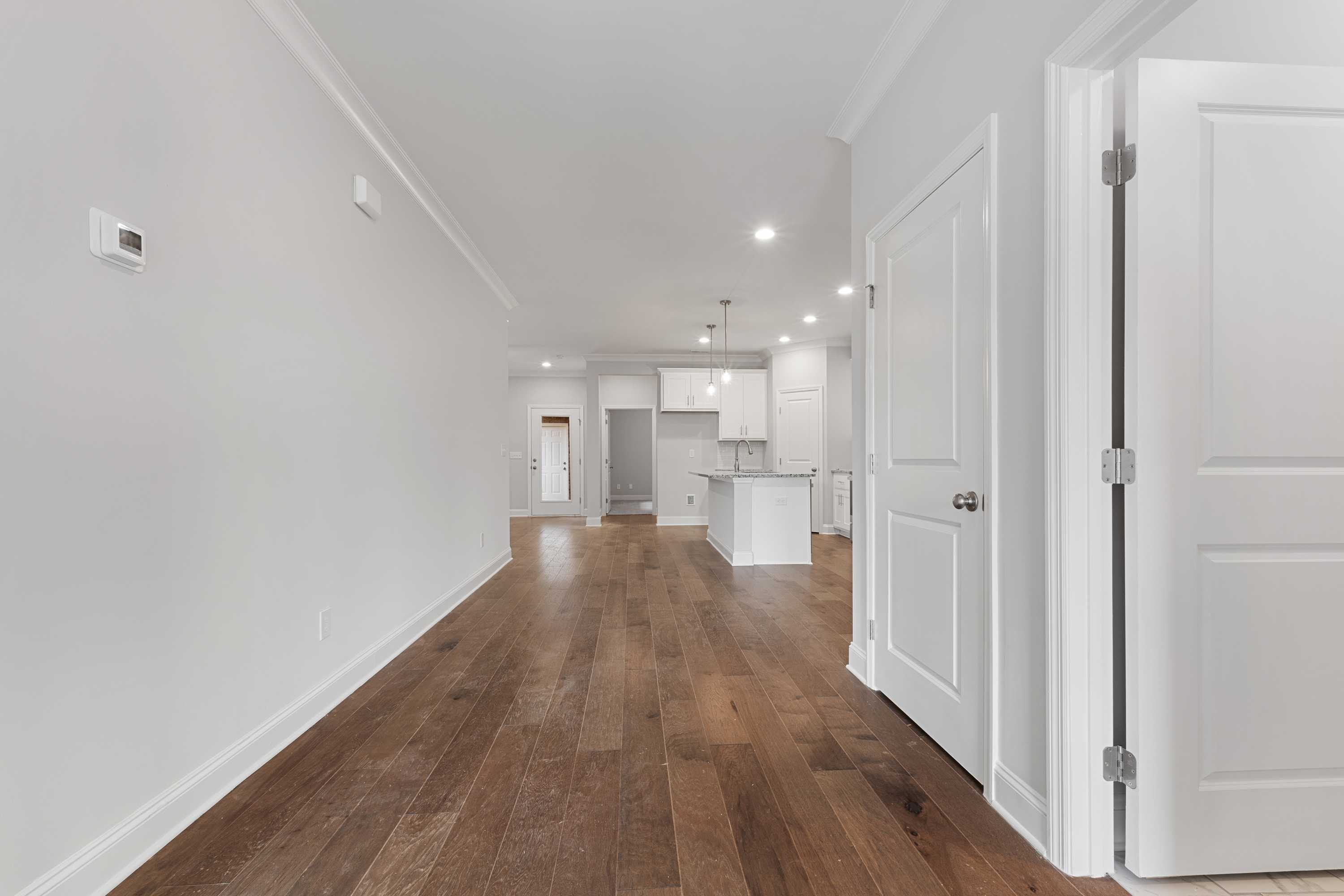 Open-concept living space in The Copeland B showcasing hardwood floors, white kitchen island, and recessed lighting