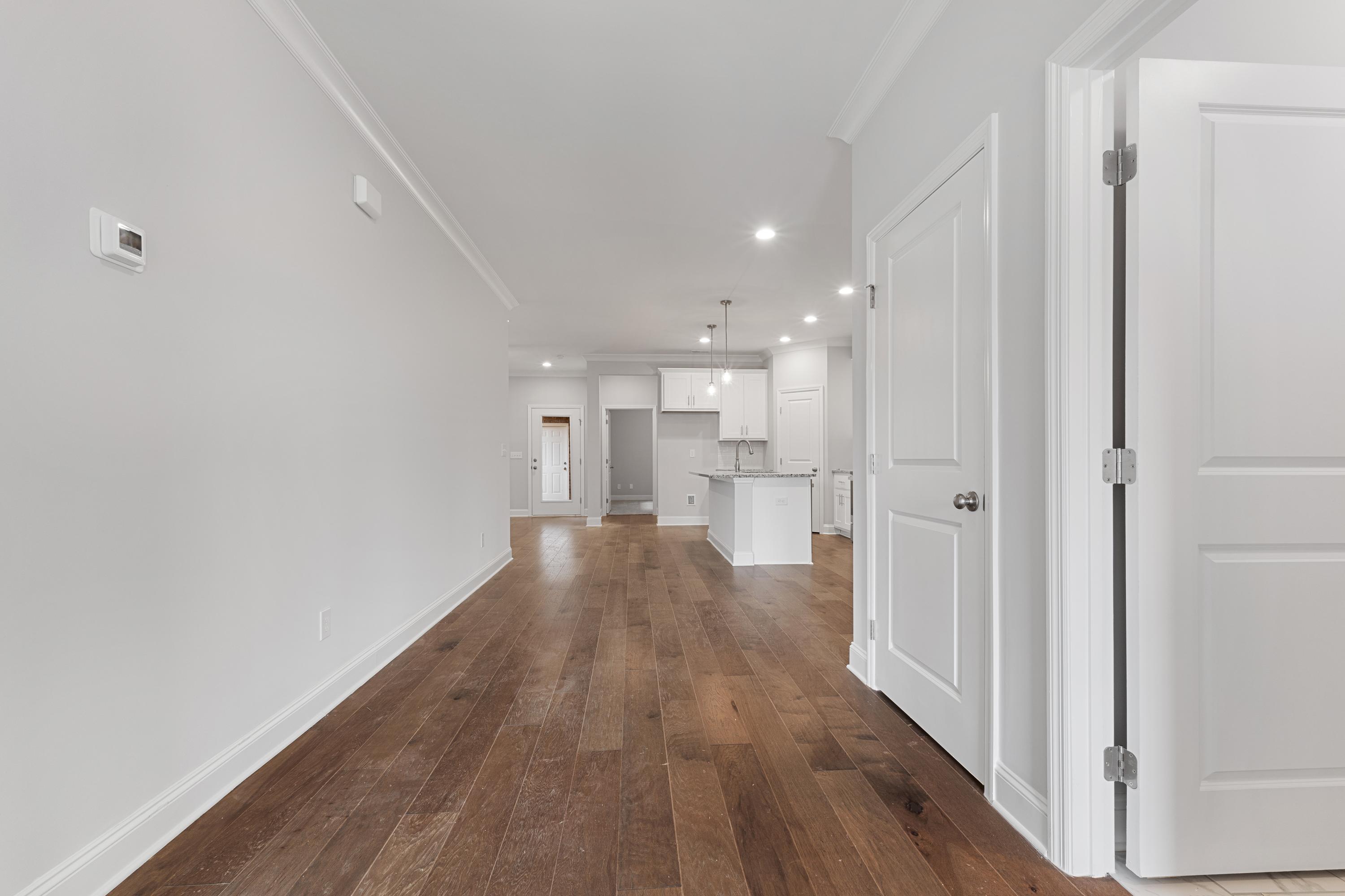 Spacious hallway with hardwood floors leading to open white kitchen in The Copeland C 2-bedroom home, Madison AL