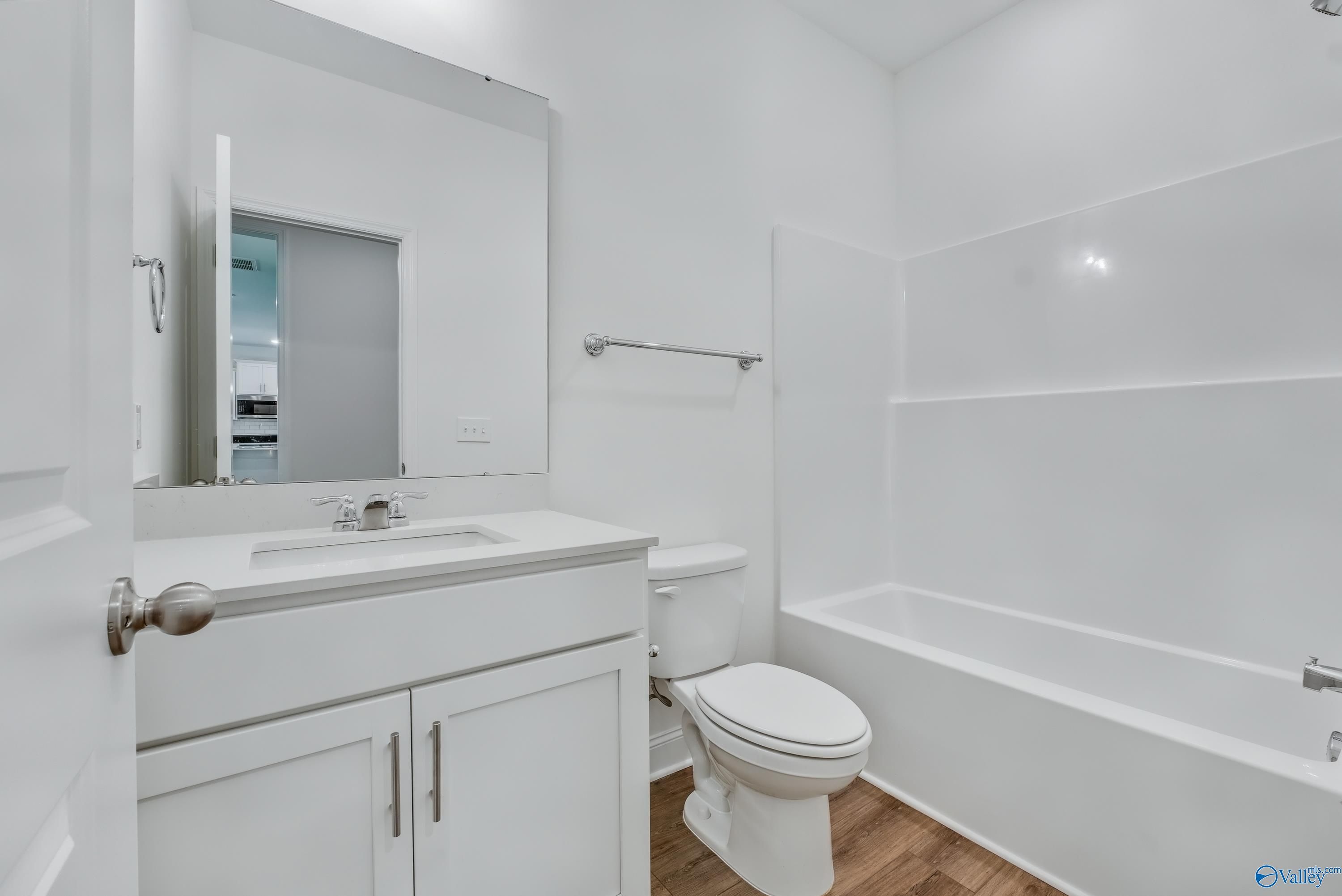 Bright white bathroom with bathtub, vanity sink, mirror, and toilet in The Shelby A 4-bedroom home, Arab, Alabama