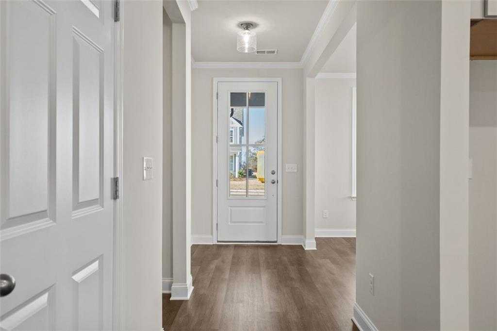 Bright entry hallway with glass-panel front door, hardwood floors, and neutral walls in Davidson Homes The Ash C, Wehunt Meadows, Hoschton
