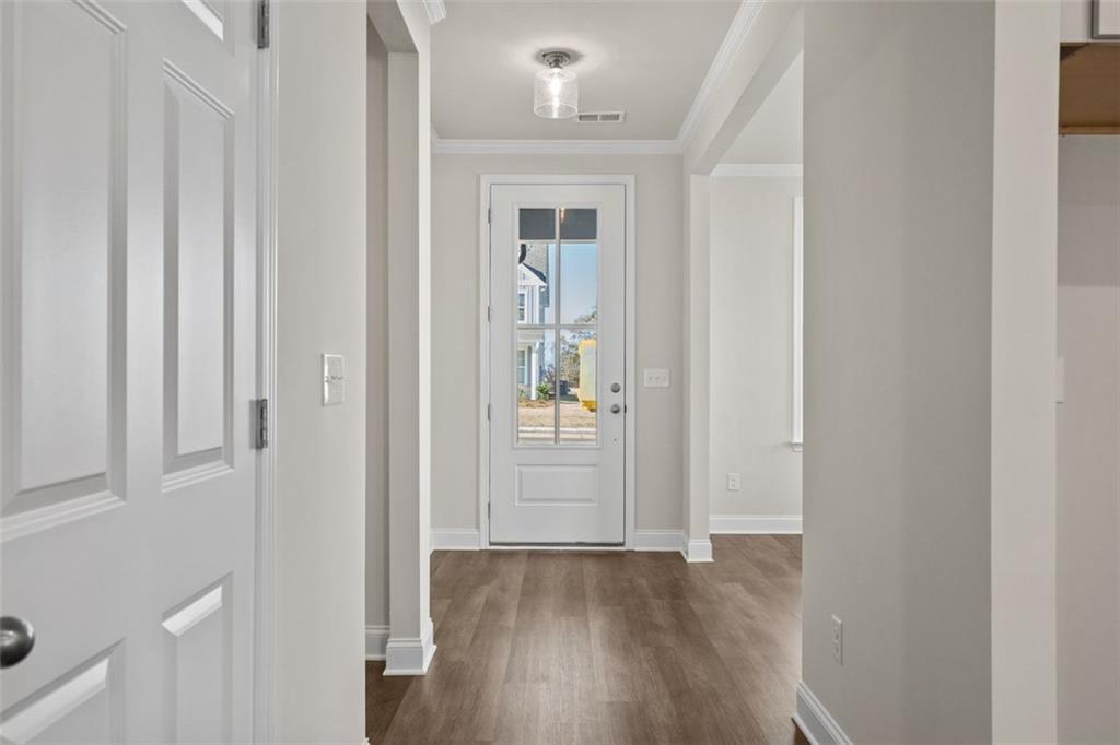 Bright entry hallway with glass-panel front door, hardwood floors, and neutral walls in Davidson Homes The Ash C, Wehunt Meadows, Hoschton