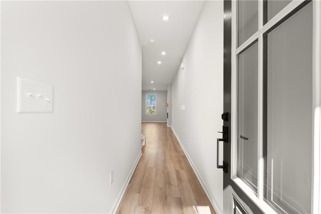 Bright hallway with white walls, hardwood floors, and recessed lighting in Davidson Homes The Cary A, Winder, Georgia
