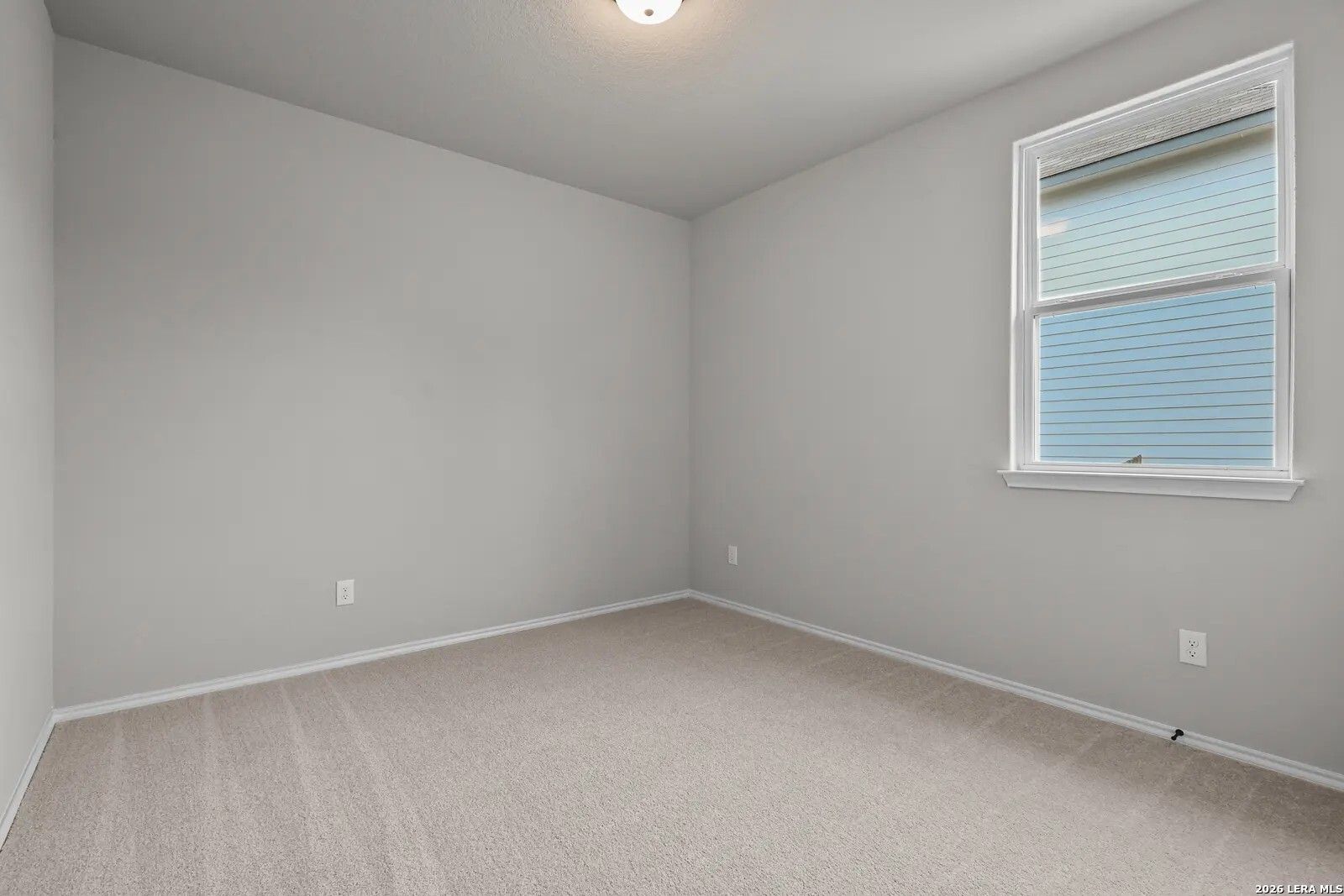 Bright, carpeted bedroom with neutral walls in The Glenwood E floor plan at Comanche Ridge, San Antonio, Texas.