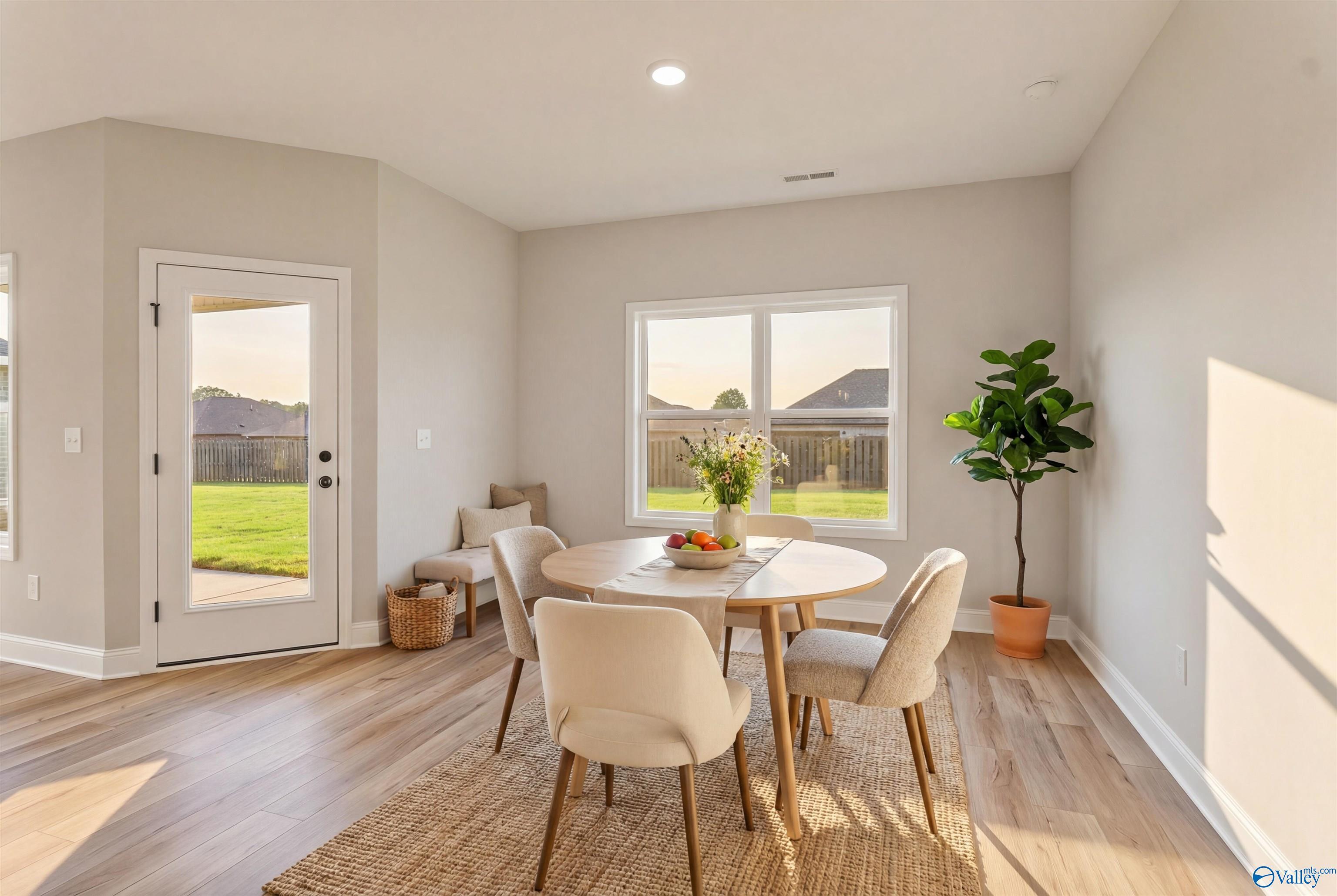 Bright dining room with round wooden table, fruit bowl, potted plant, and backyard view in Davidson Homes The Franklin B, Hazel Green, Alabama