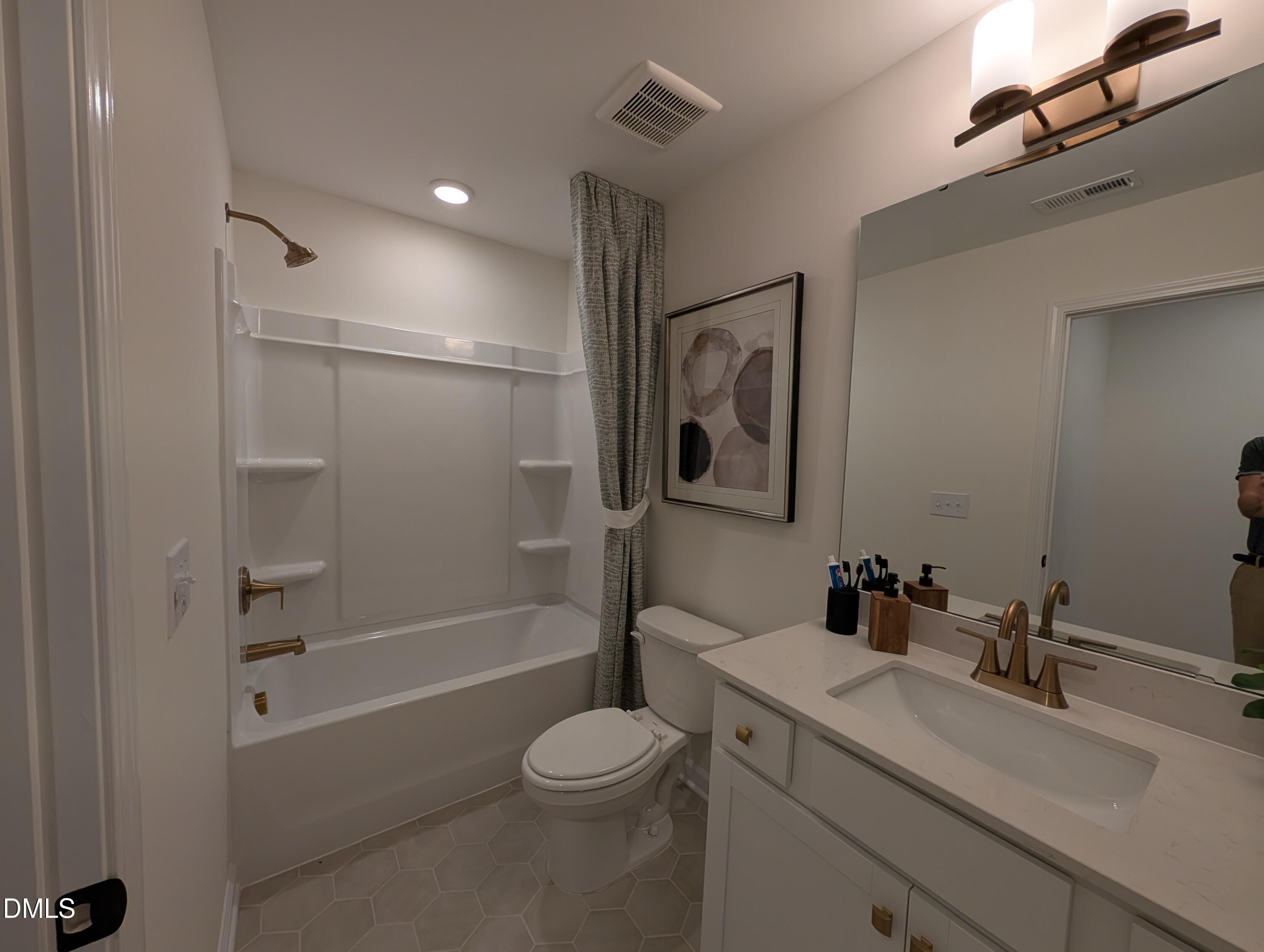 Modern bathroom with gold fixtures, white vanity, and tub-shower combo in The Aspen B model at Wendell Ridge, Wendell, NC.