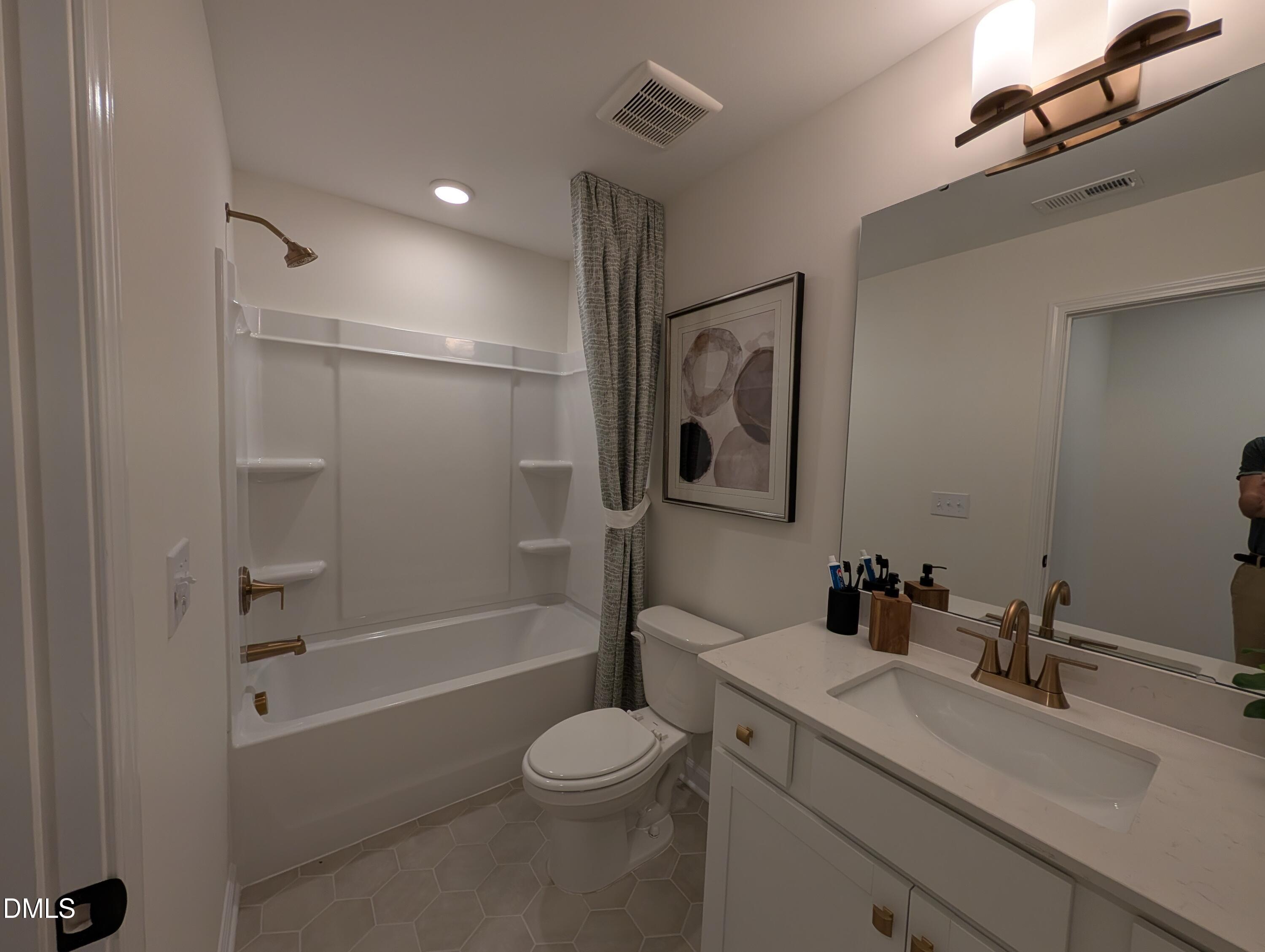 Modern bathroom with gold fixtures, white vanity, and tub-shower combo in The Aspen B model at Wendell Ridge, Wendell, NC.