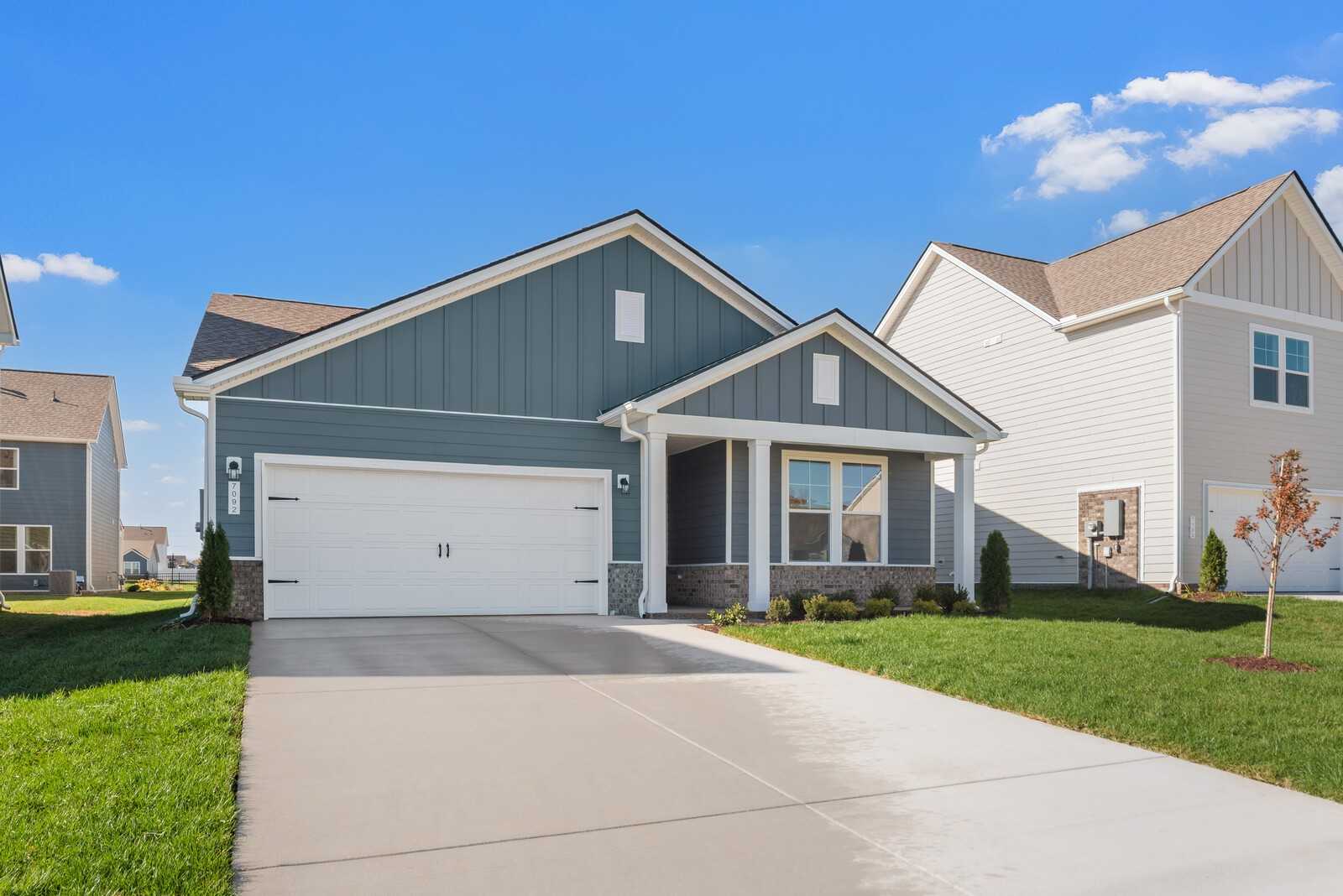 Modern blue-gray single-story home with 2-car garage, covered porch, driveway, and landscaped yard in Davidson Homes The Franklin B, Sage Farms, White House, TN