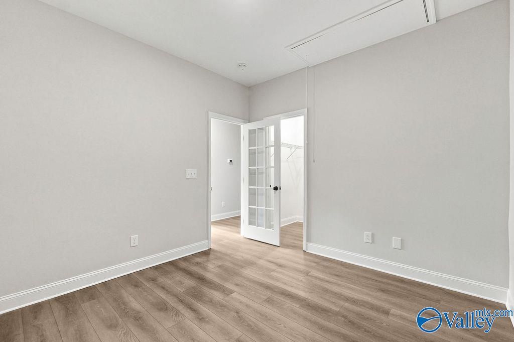 Bedroom with light grey walls, wood-look flooring, and French door closet in The Camilla C home at The Retreat at Cain Park.