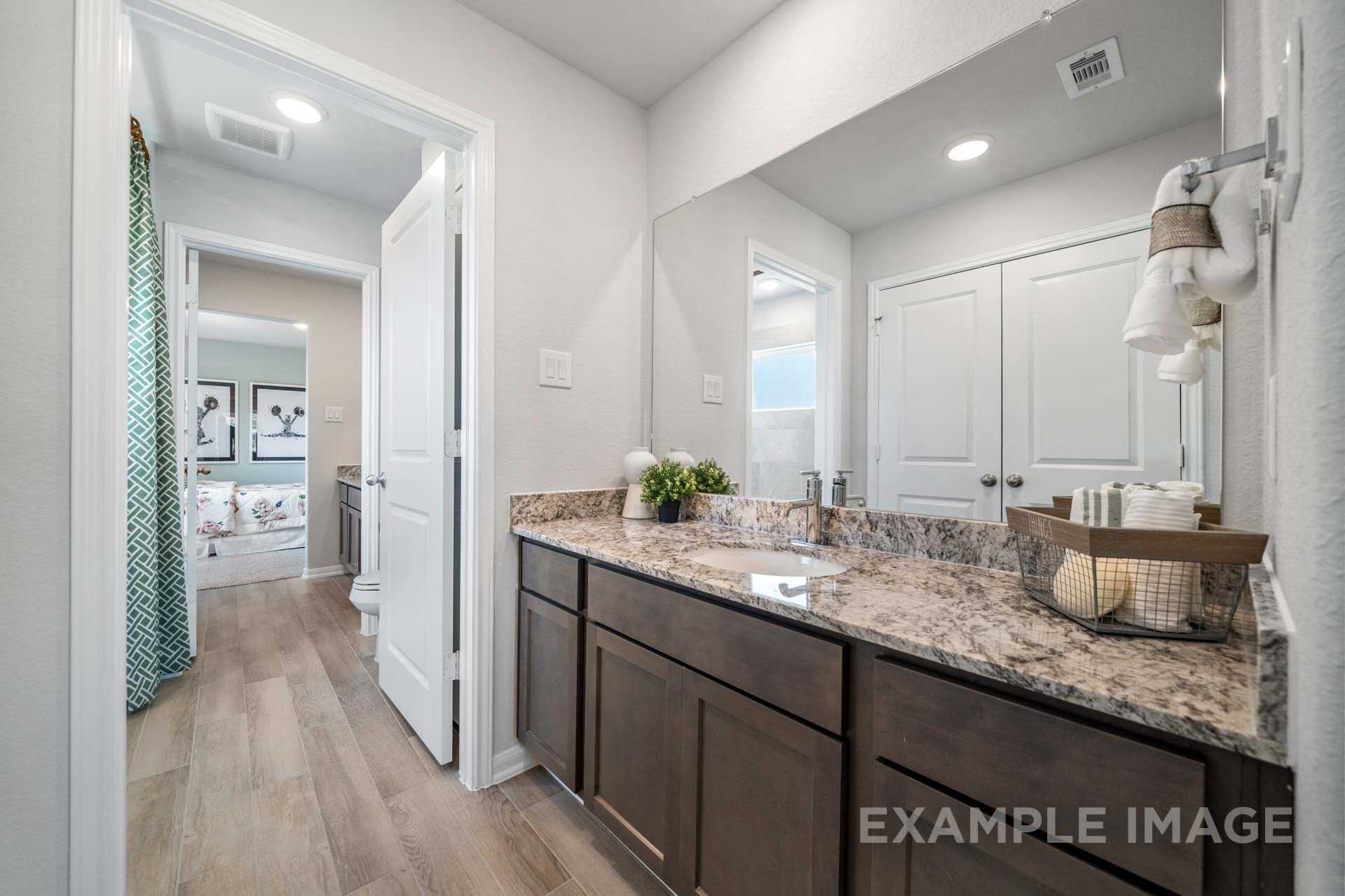 Spacious master bathroom in The Acadia A featuring double vanity with granite counters, wood cabinets, and walk-in shower