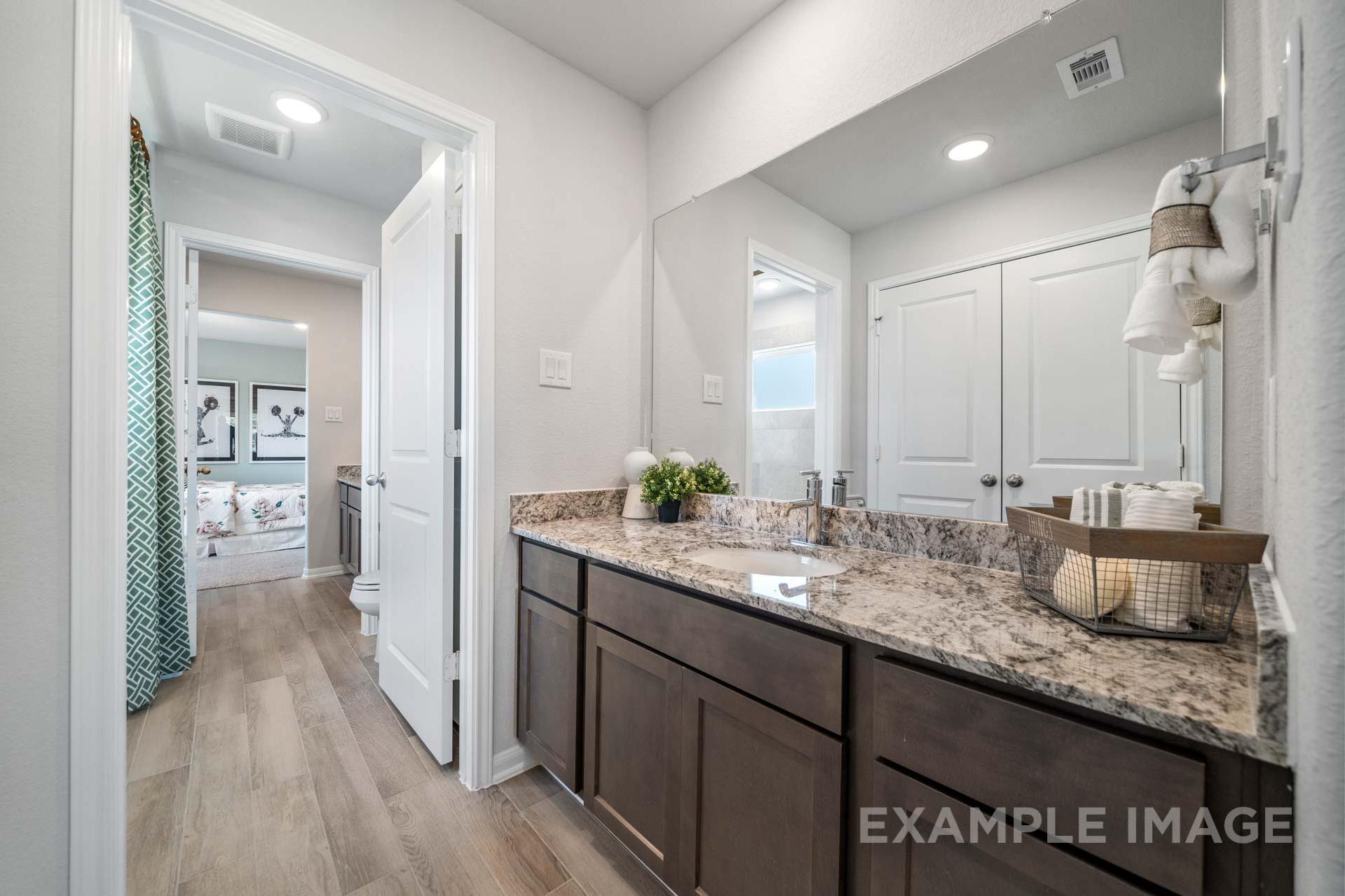 Spacious master bathroom in The Acadia A featuring double vanity with granite counters, wood cabinets, and walk-in shower