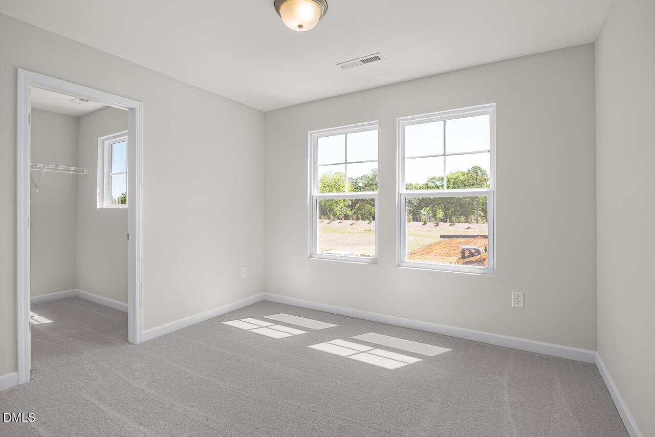 Bright bedroom with carpet and walk-in closet in The Grace C floor plan at Retreat at North Main, Lillington, NC.