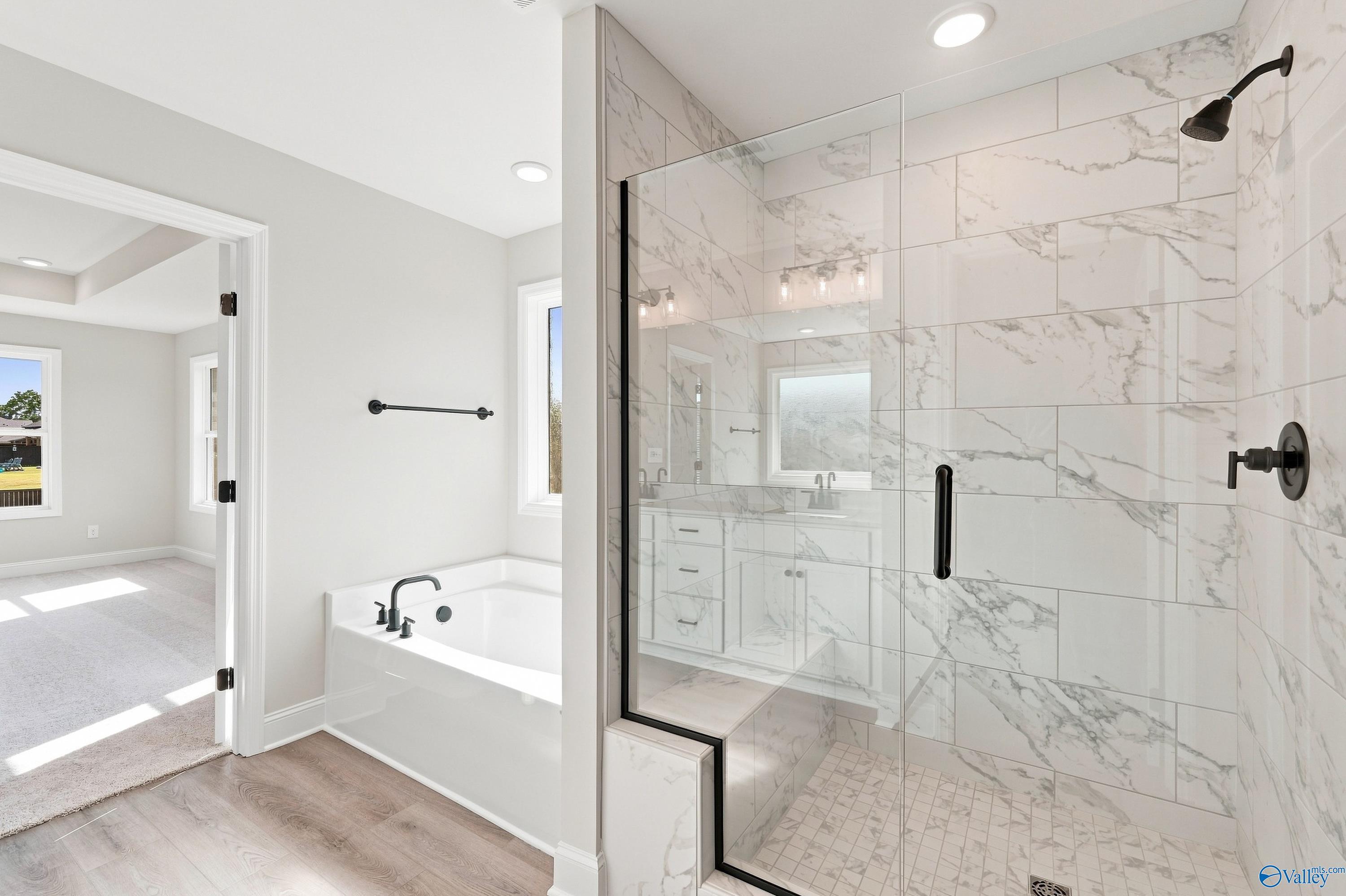 Modern master bathroom with marble tile walk-in shower, garden tub, and matte black fixtures in Davidson Homes Chelsea B, New Market, AL