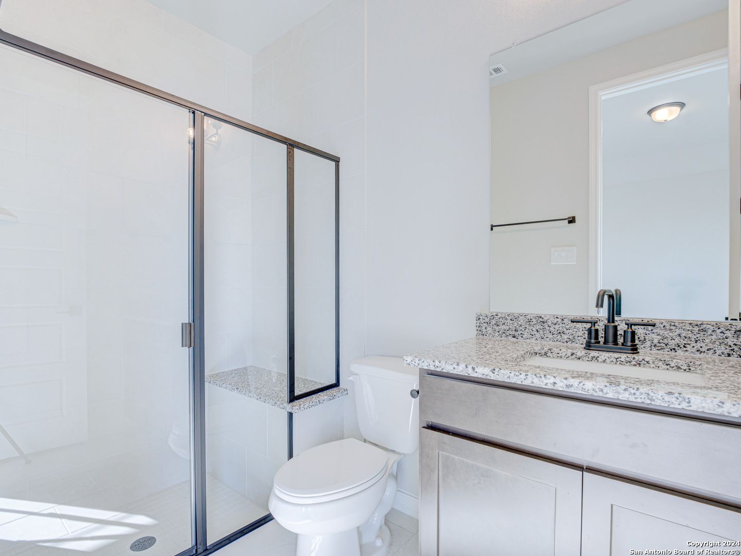 Modern bathroom featuring glass shower enclosure, granite countertop vanity, and stainless faucet in Davidson Homes The Summerlin A, Castroville, Texas