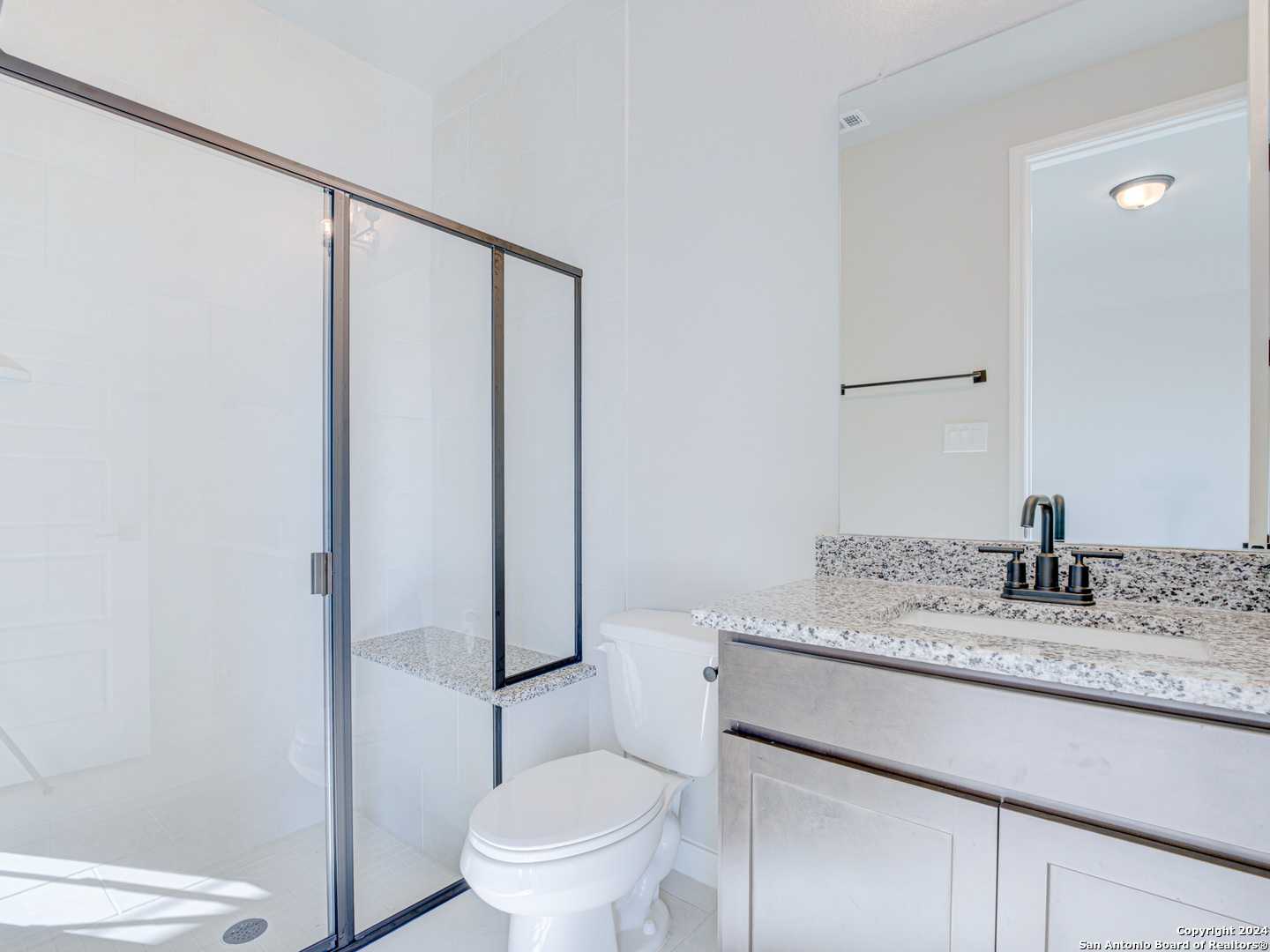 Modern bathroom featuring glass shower enclosure, granite countertop vanity, and stainless faucet in Davidson Homes The Summerlin A, Castroville, Texas