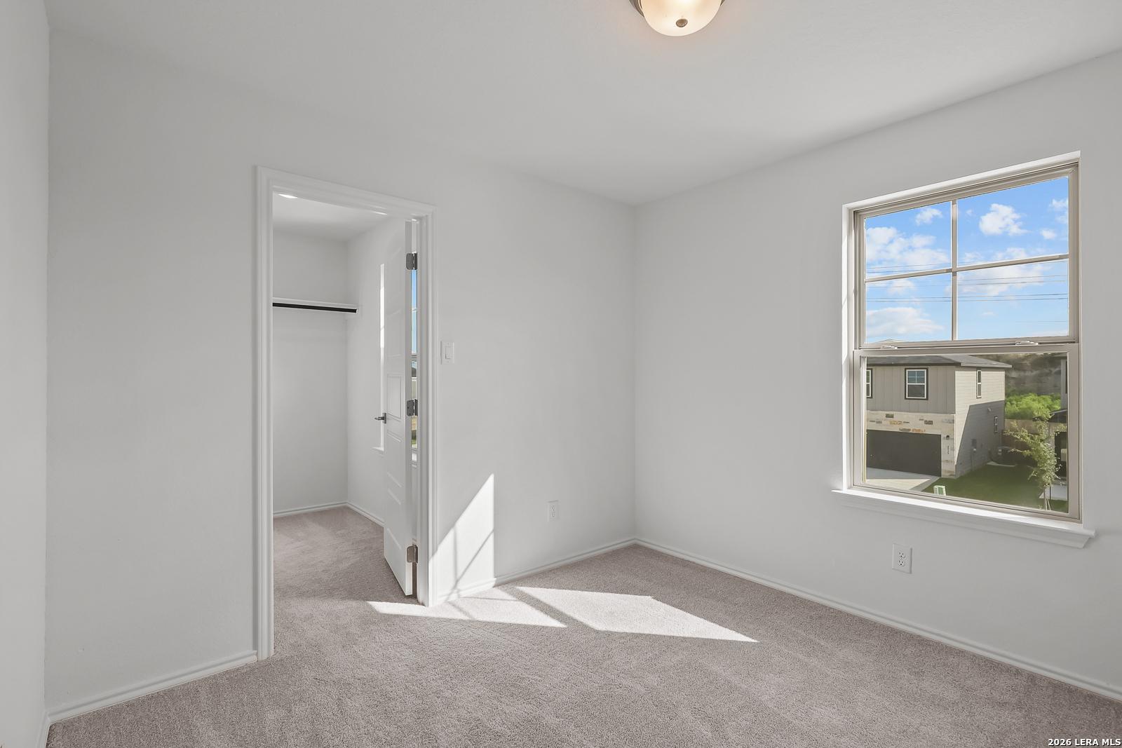 Bright bedroom with carpet and walk-in closet in The Brazos B floor plan by Davidson Homes in Agave, San Antonio, Texas.