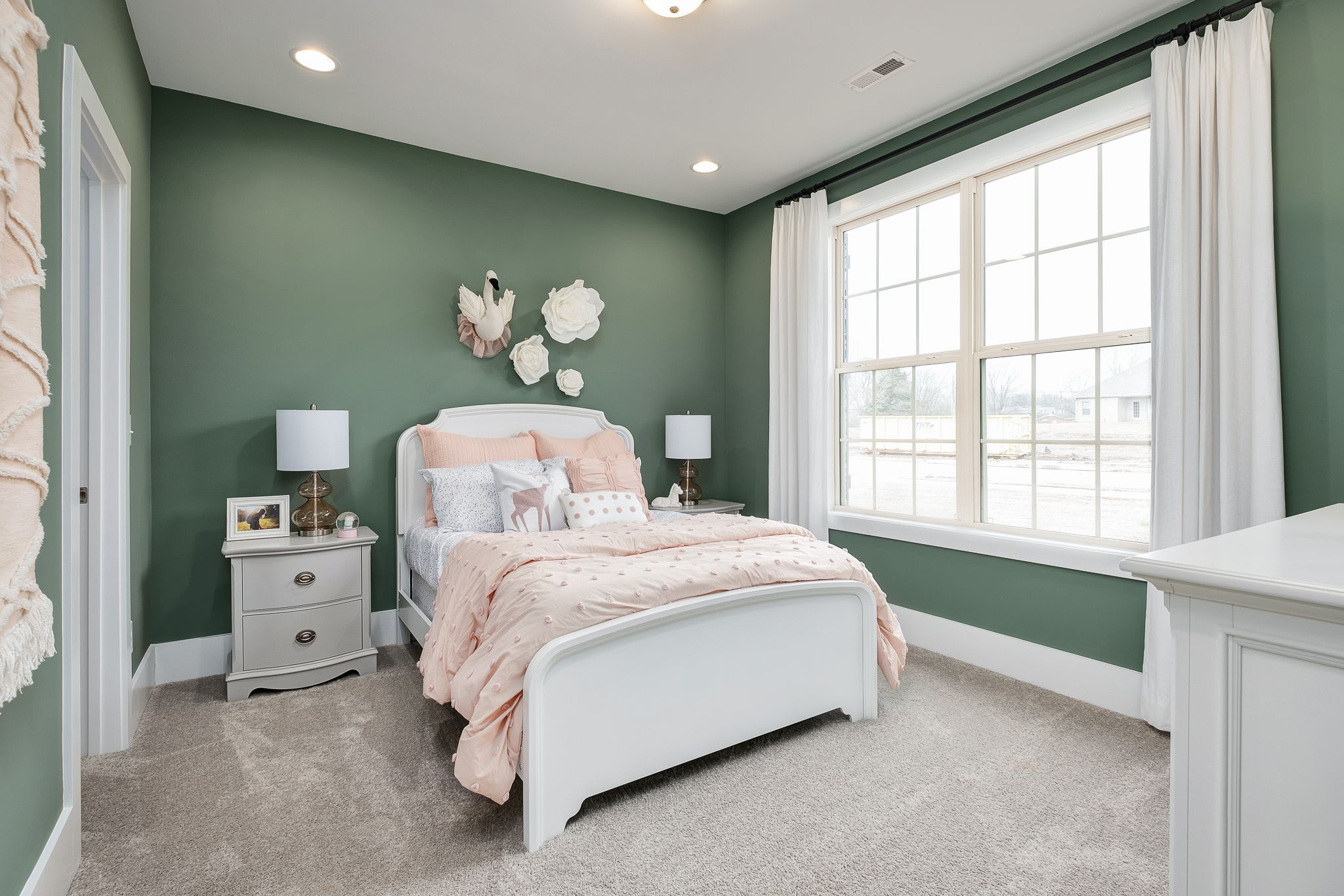 Cozy girl's bedroom in Chimney Creek, Hampton Cove AL with sage green walls, white bed, pink bedding and swan wall art
