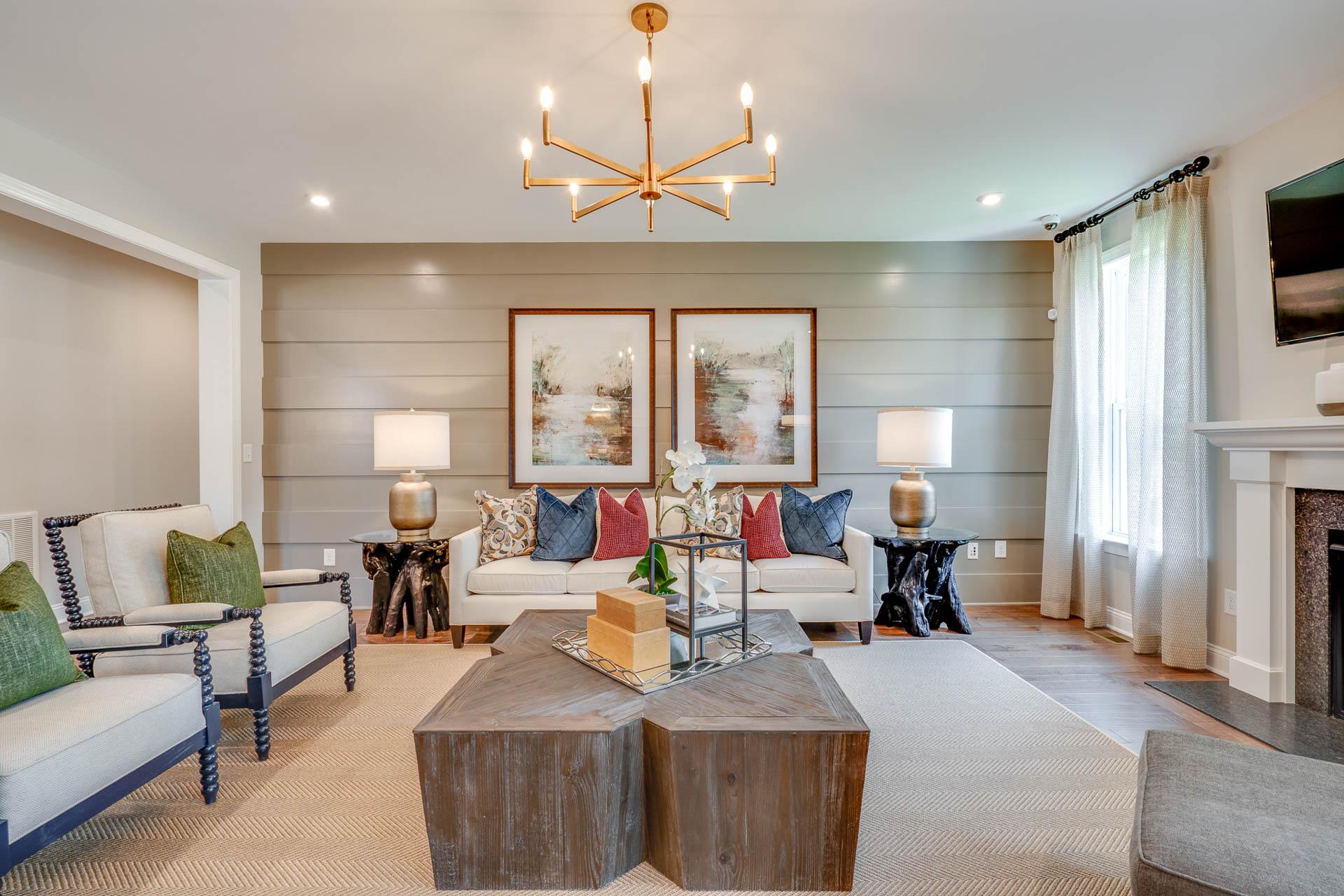 Cozy living room in Hasentree featuring shiplap accent wall, modern chandelier, plush sofa, coffee table, and fireplace in Wake Forest NC