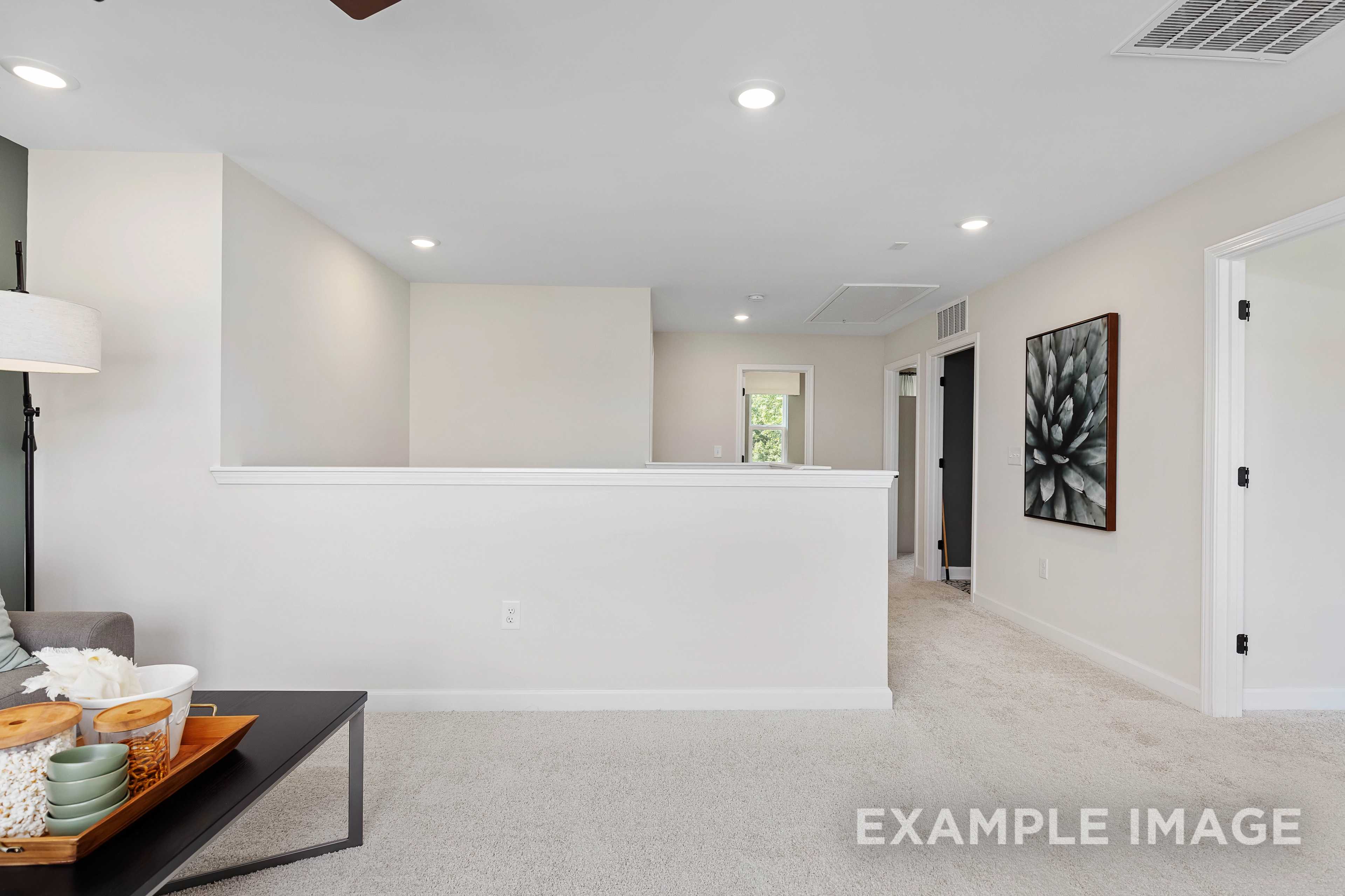 Spacious upper floor loft in The Willow B home featuring open hallway, beige walls, recessed lighting, and modern railing overlook