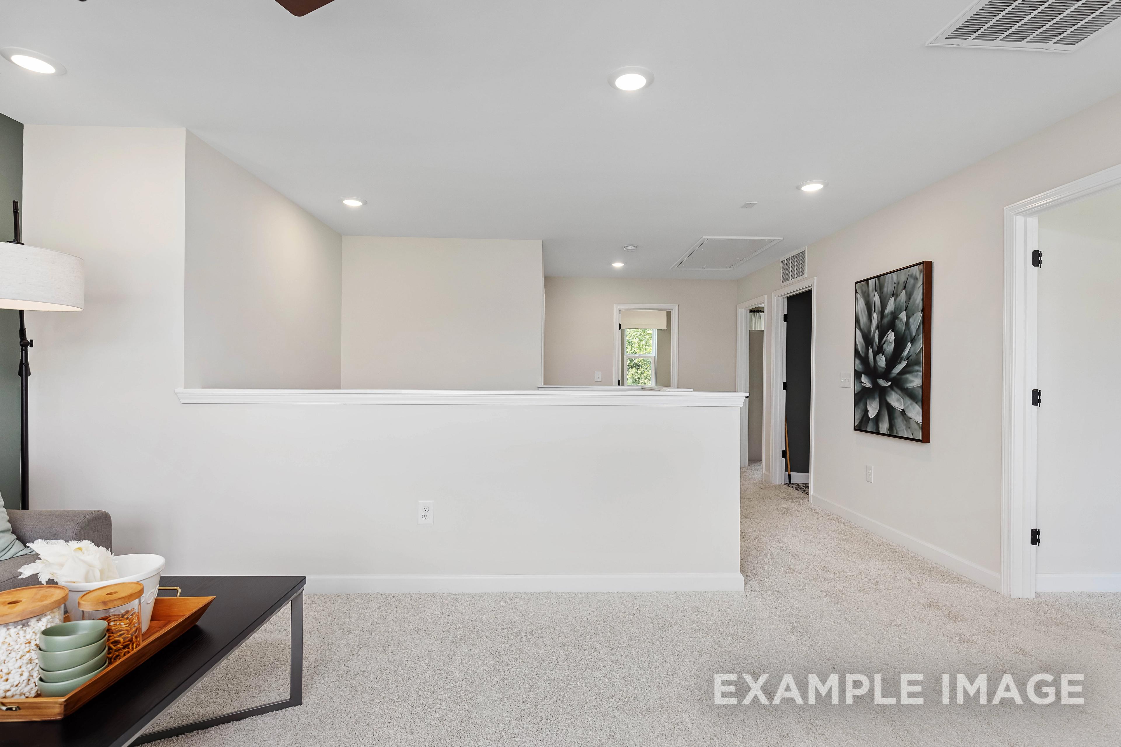 Spacious upper floor loft in The Willow B home featuring open hallway, beige walls, recessed lighting, and modern railing overlook