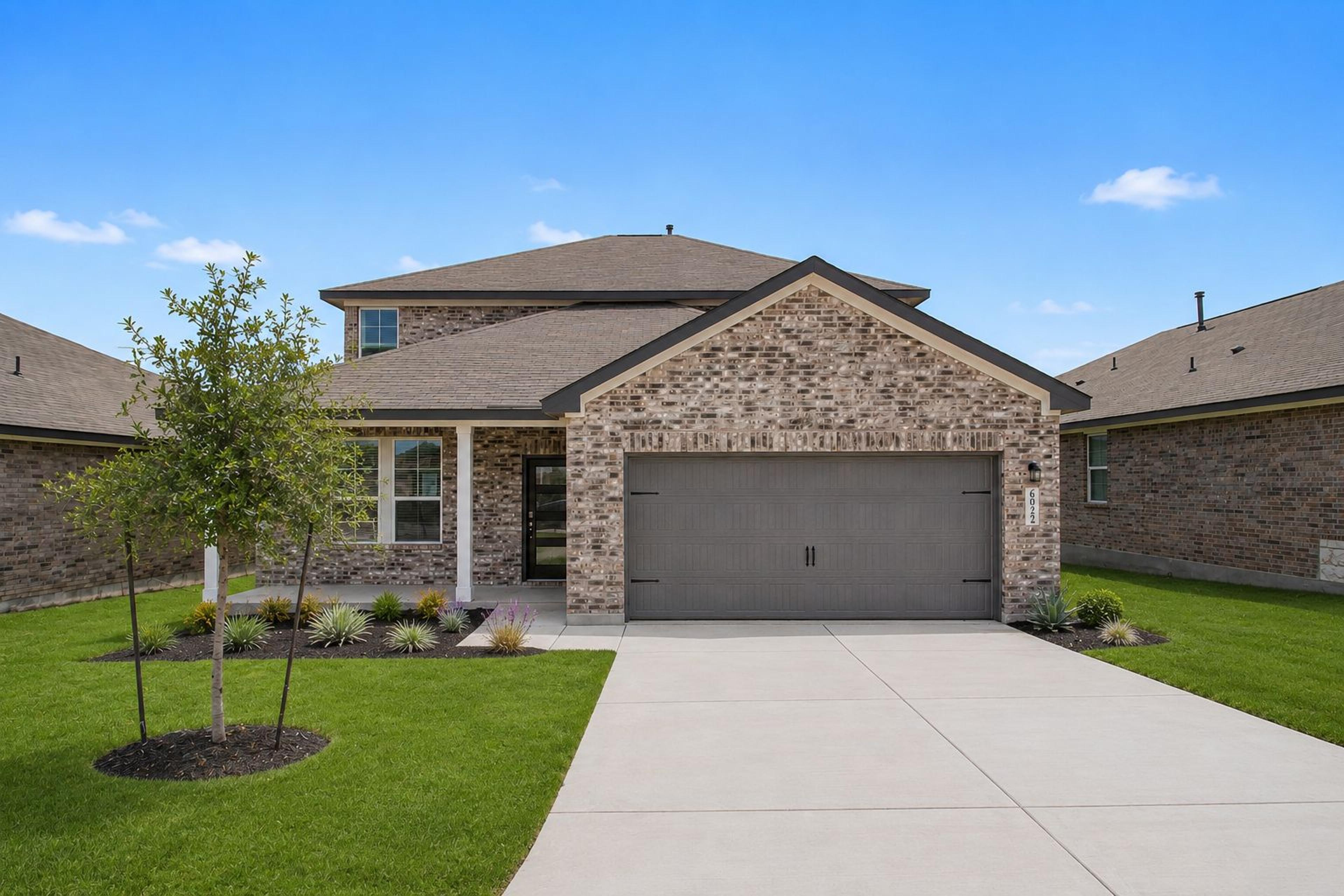 Davidson Homes exterior with brick facade and two-car garage at Comanche Ridge in San Antonio, Texas.