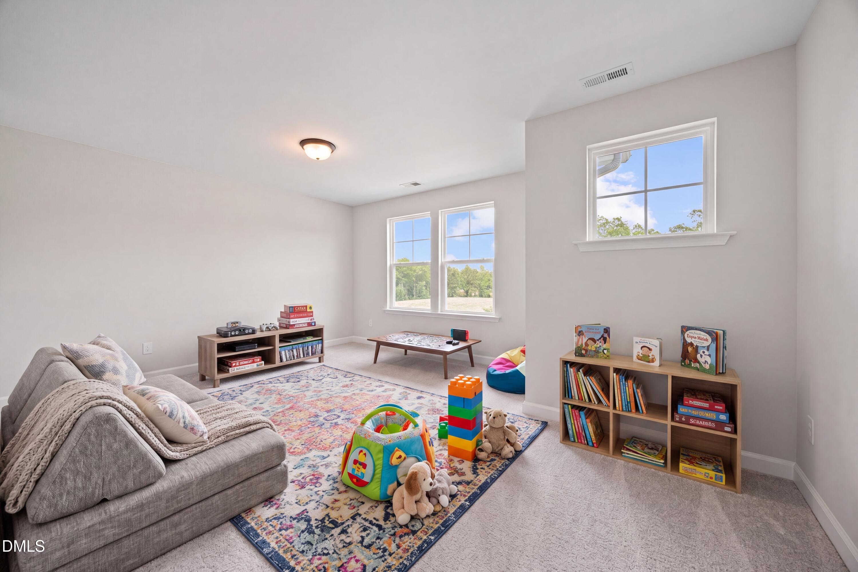 Spacious carpeted playroom with kids' toys and area rug in The Willow D floor plan at Wendell Ridge, Wendell, NC.