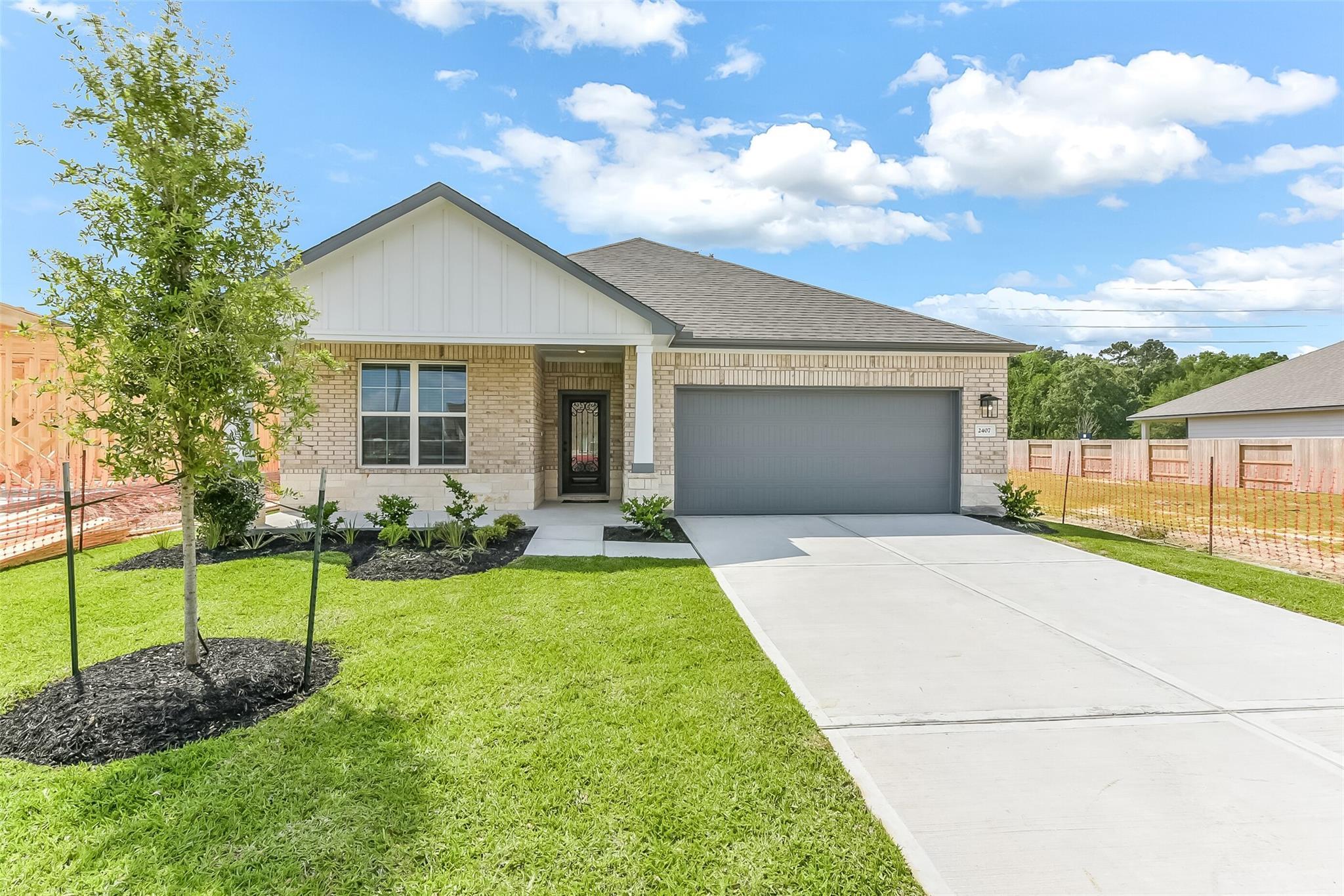 Modern beige brick single-story home with 2-car garage, front porch, and landscaped yard in Sundance Cove, Crosby, Texas - Everett C by Davidson Homes