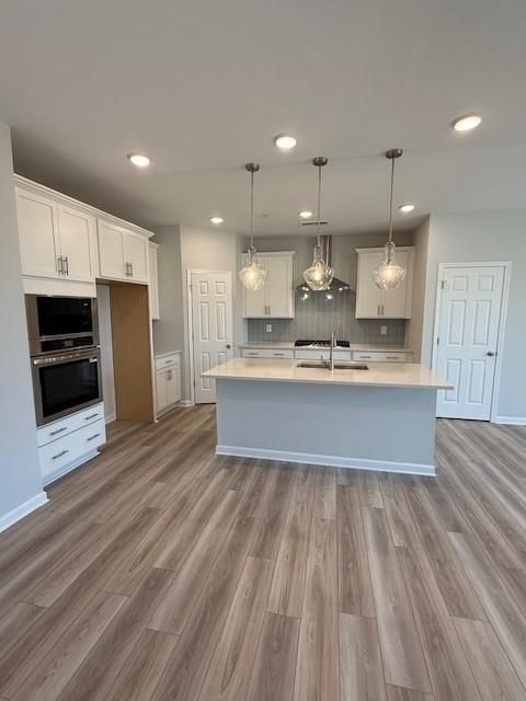 Modern white shaker kitchen with large center island, subway tile backsplash, and pendant lights in Davidson Homes The Durham D, Cumming, GA