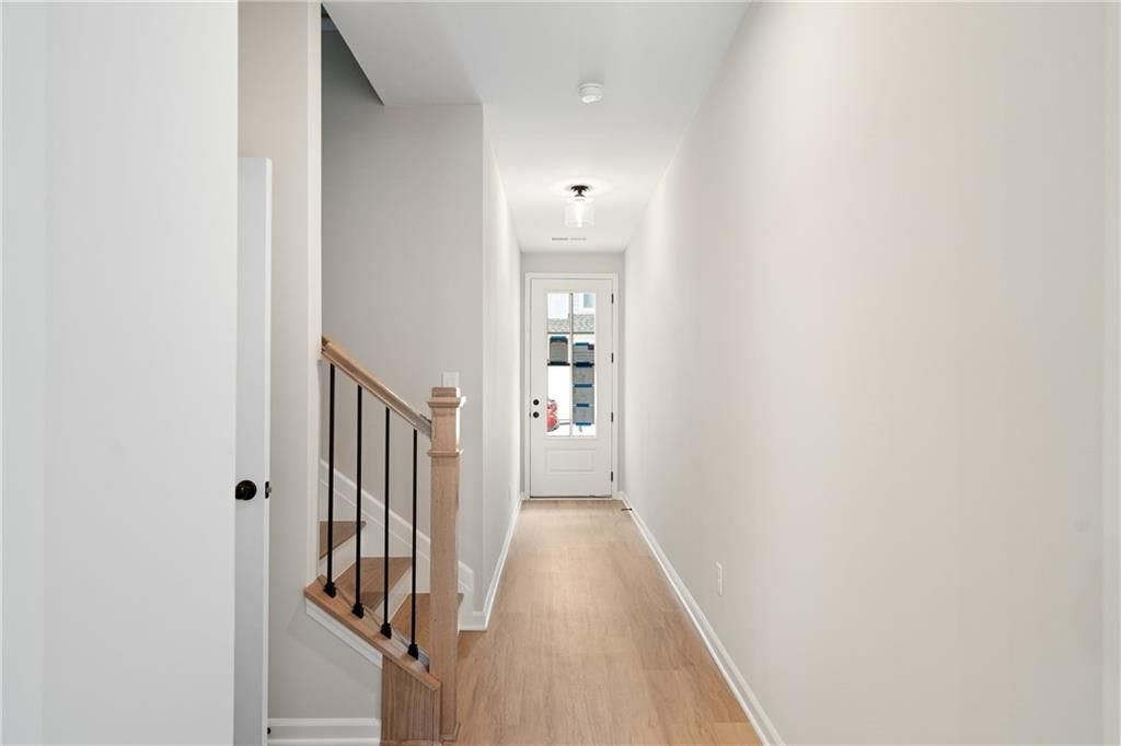 Bright foyer hallway with oak staircase, wrought iron balusters, and glass-front door in The Marion A by Davidson Homes, Kennesaw, GA