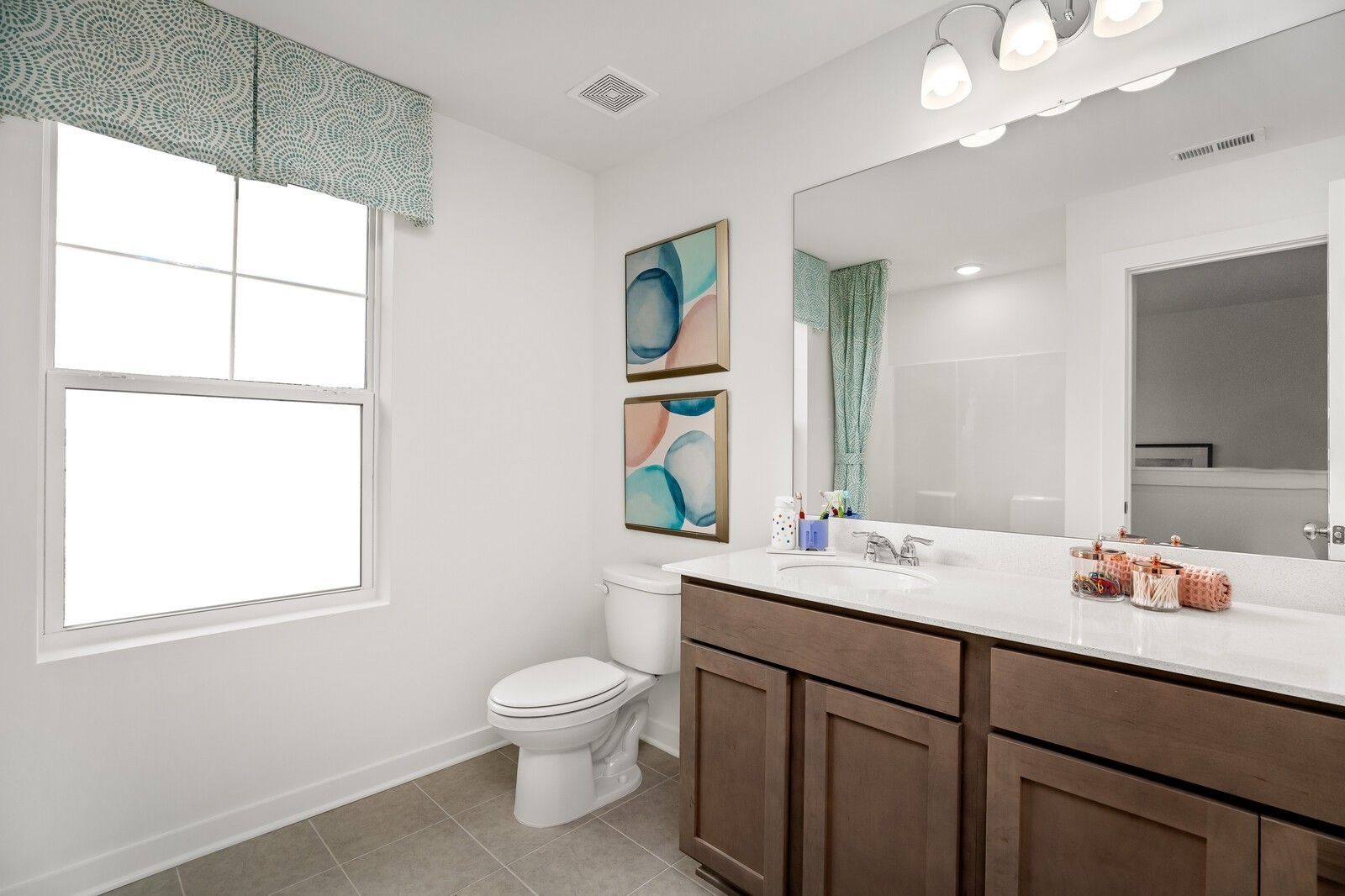 Modern bathroom with dark wood vanity, quartz countertop, and patterned window valance in The Gordon C, Sage Farms home.