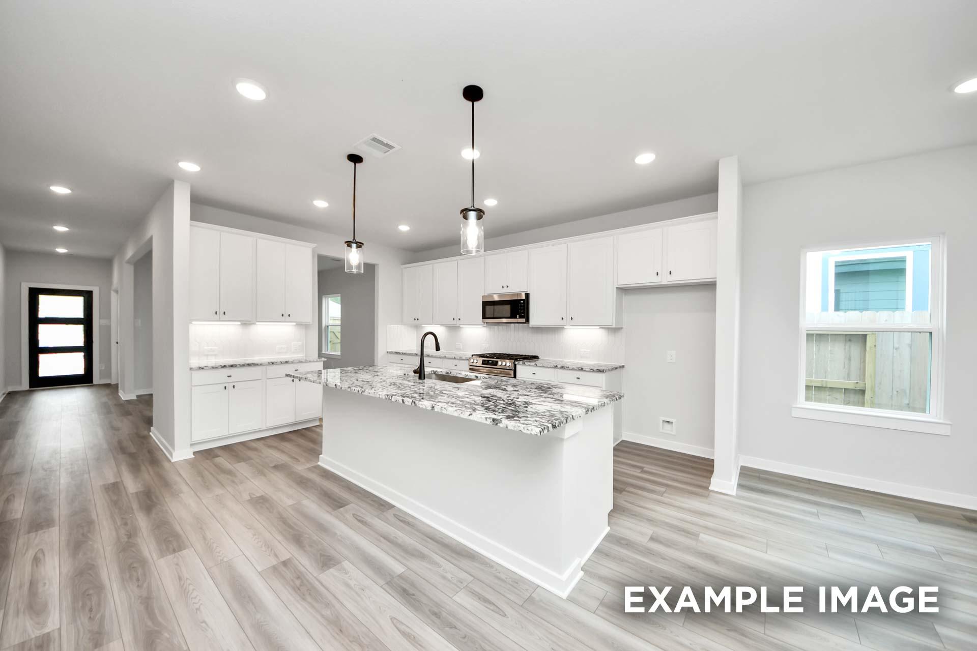 Modern white kitchen in The Sorrento F featuring a granite island, pendant lighting, and sleek wood-look flooring.