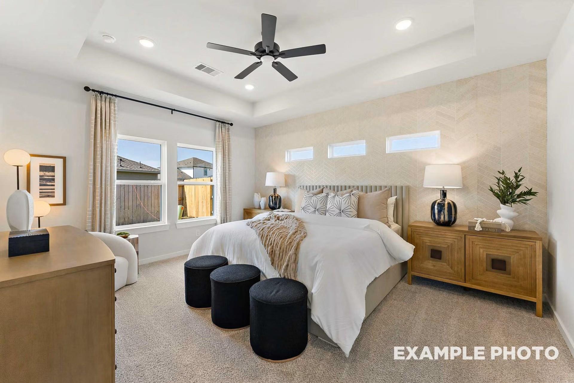 Elegant master bedroom with king bed, ceiling fan, large windows, and textured wall in Davidson Homes The Everett C, Dayton, Texas