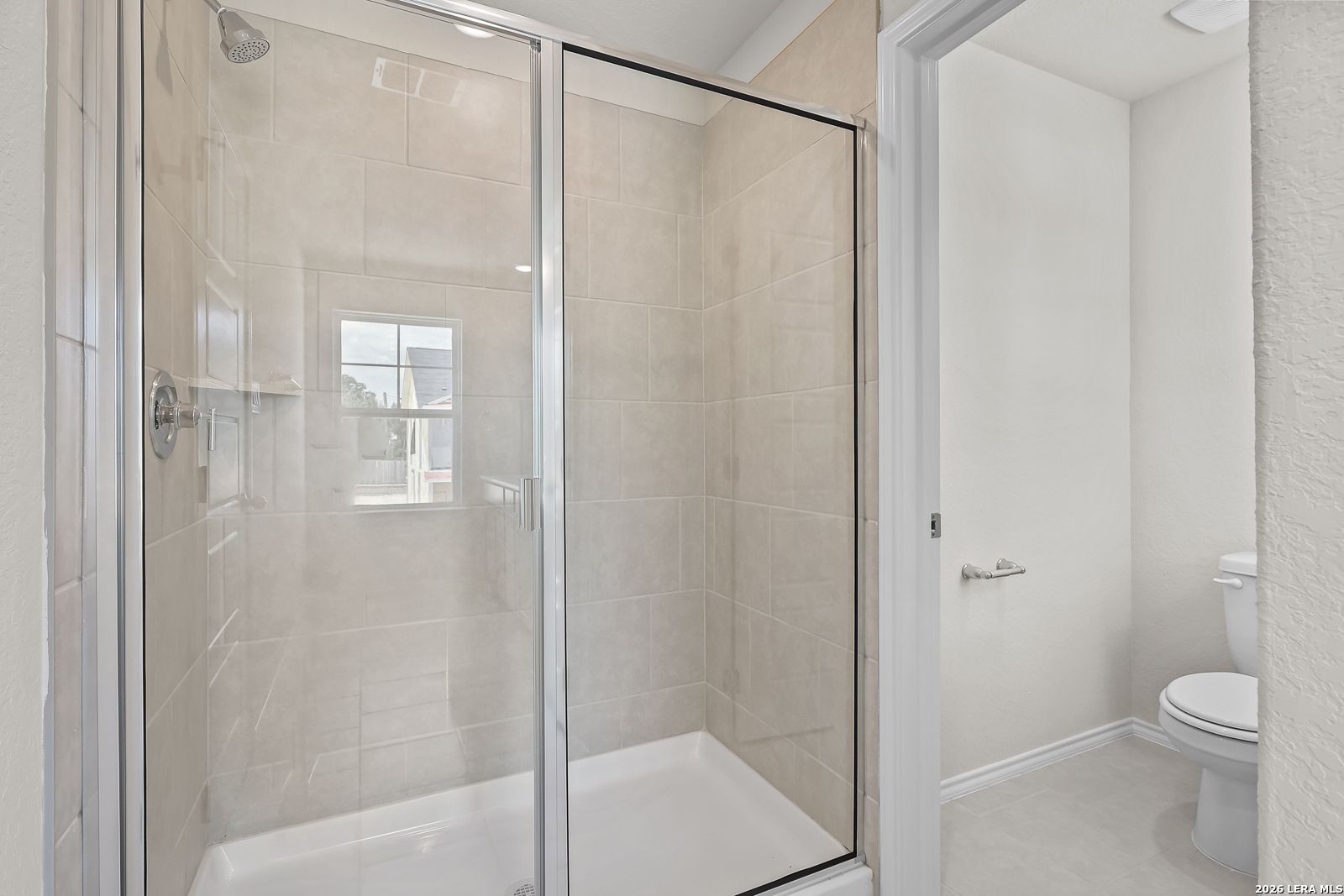 Walk-in tile shower and private toilet area in The Gillian B floor plan at Meadows at Oak Creek, San Antonio, Texas.
