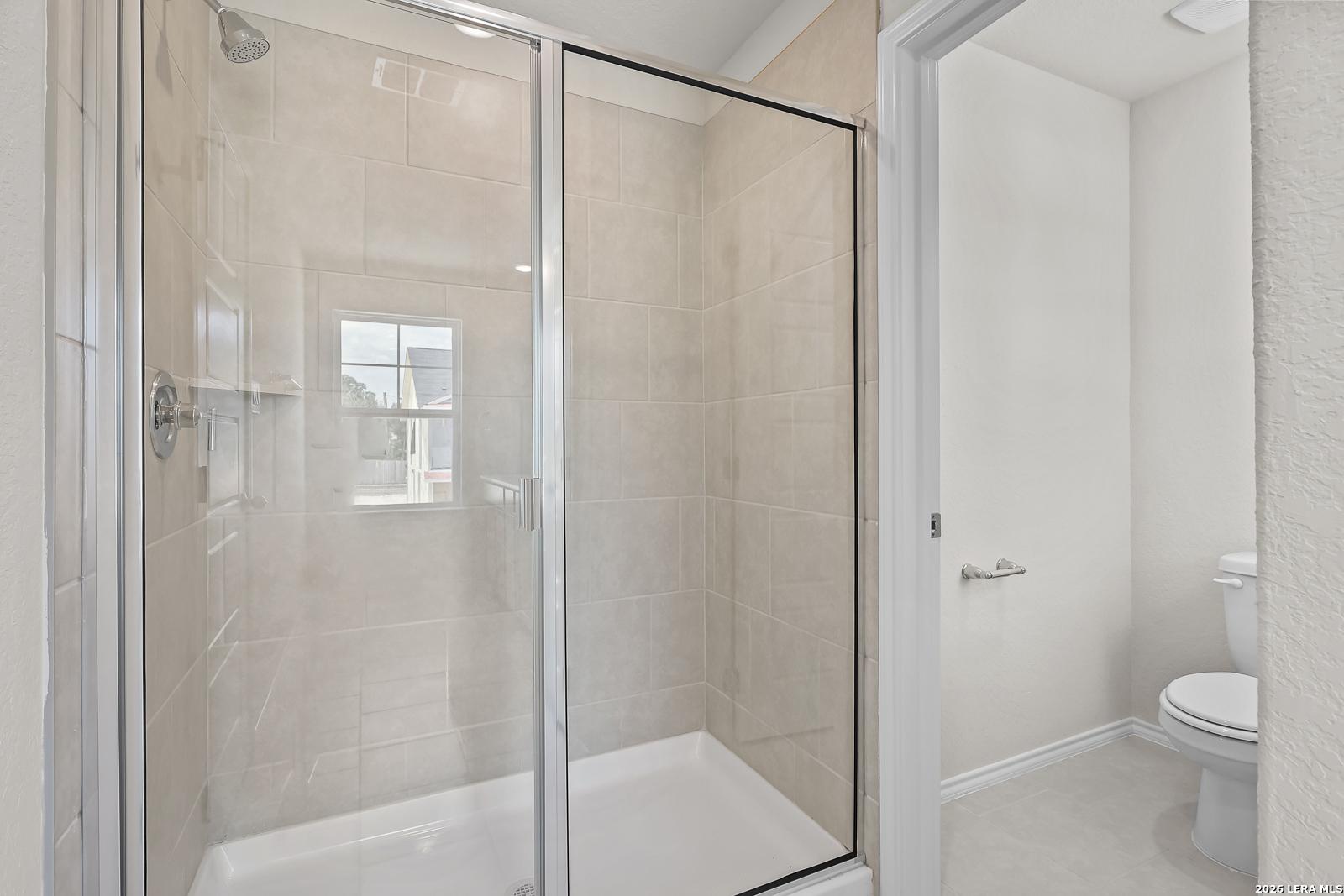 Walk-in tile shower and private toilet area in The Gillian B floor plan at Meadows at Oak Creek, San Antonio, Texas.