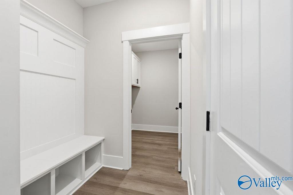 Bright mudroom with white built-in lockers, bench seating, open shelves, and hardwood floors in Davidson Homes The Rockford, Hartselle, Alabama