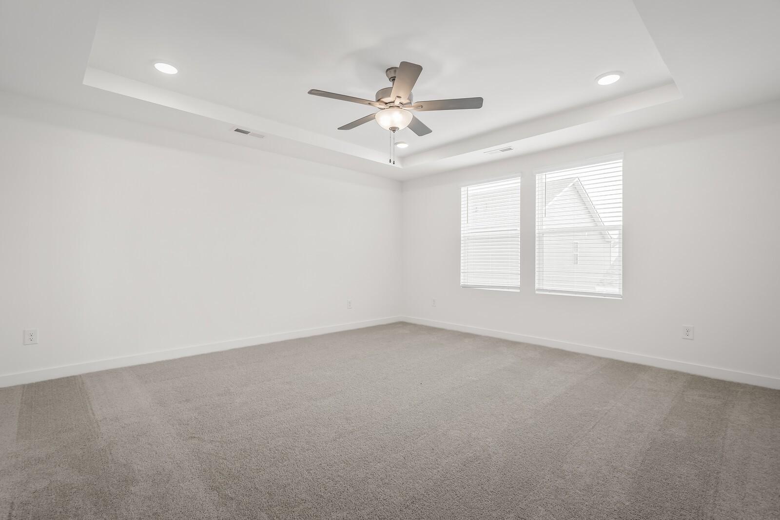 Bright empty bedroom with beige carpet, ceiling fan, recessed lights, and double windows in Davidson Homes The Gordon C, White House, TN