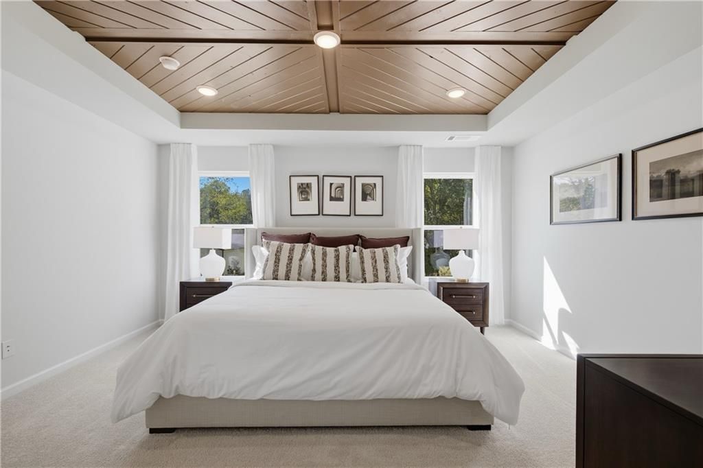 Bright primary bedroom with wood-plank ceiling, dual windows, and nightstands in Davidson Homes Sinclair B, Cartersville, Georgia