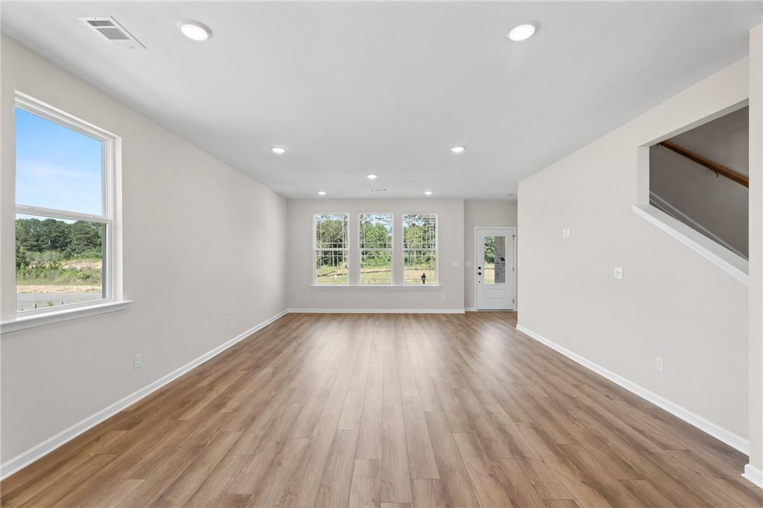 Bright, open-concept living area with wood-style flooring in The Stella C floor plan at Links Crossing, Auburn, Alabama.