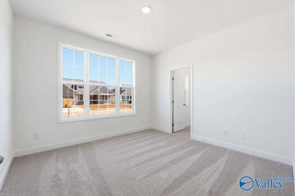 Bright secondary bedroom with large window overlooking neighborhood and gray carpet in Davidson Homes The Montgomery, Hartselle, Alabama